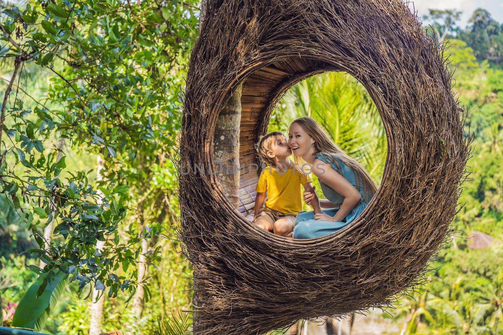 Bali trend, straw nests everywhere. Happy family enjoying their travel around Bali island, Indonesia. Making a stop on a beautiful hill. Photo in a straw nest, natural environment. Lifestyle. Traveling with kids concept. What to do with children. Child friendly place.