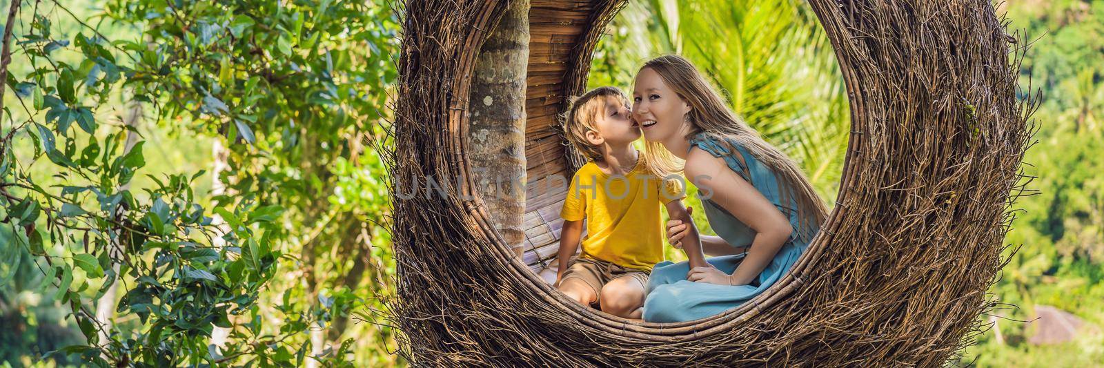 BANNER, LONG FORMAT Bali trend, straw nests everywhere. Happy family enjoying their travel around Bali island, Indonesia. Making a stop on a beautiful hill. Photo in a straw nest, natural environment. Lifestyle. Traveling with kids concept. What to do with children. Child friendly place.