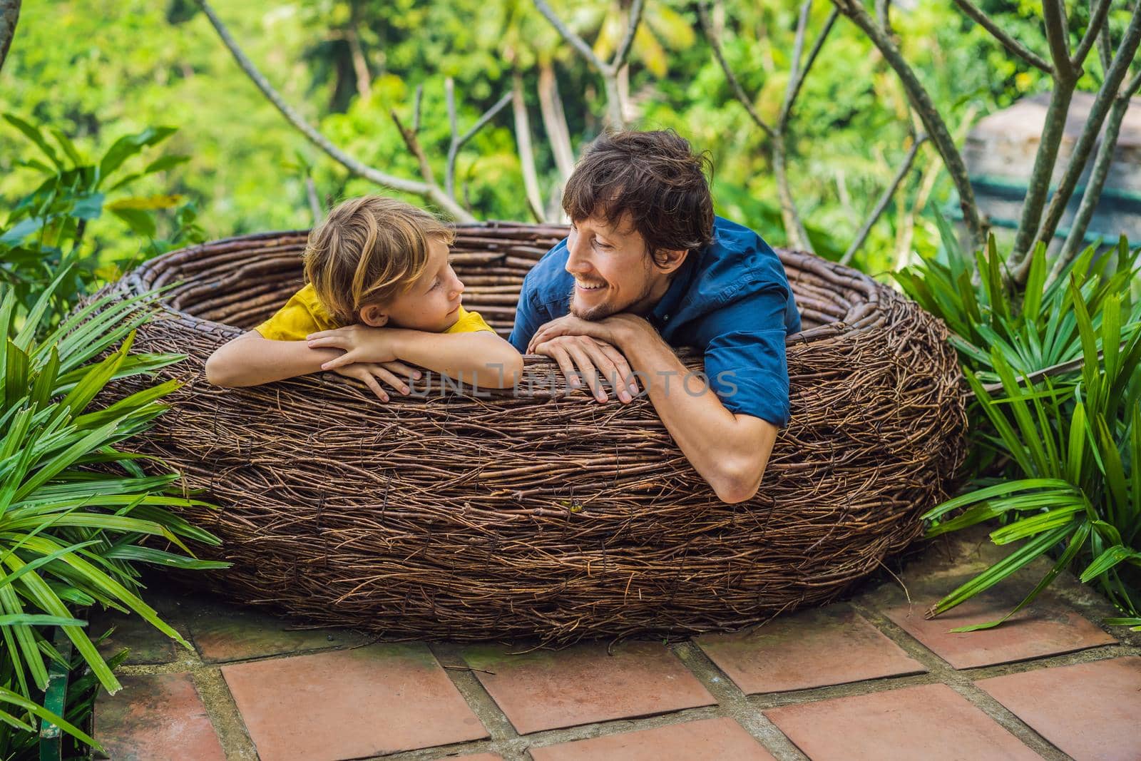 Bali trend, straw nests everywhere. Child friendly place. Happy family enjoying their travel around Bali island, Indonesia. Making a stop on a beautiful hill. Photo in a straw nest, natural environment. Lifestyle. Traveling with kids concept. What to do with children.