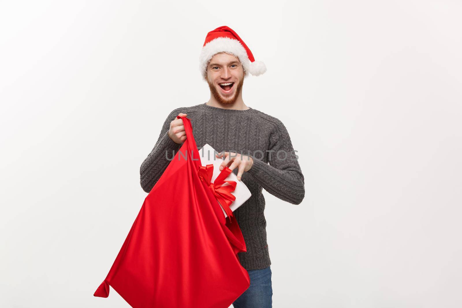 Christmas Concept - Young happy beard man excite with big present in santa bag.