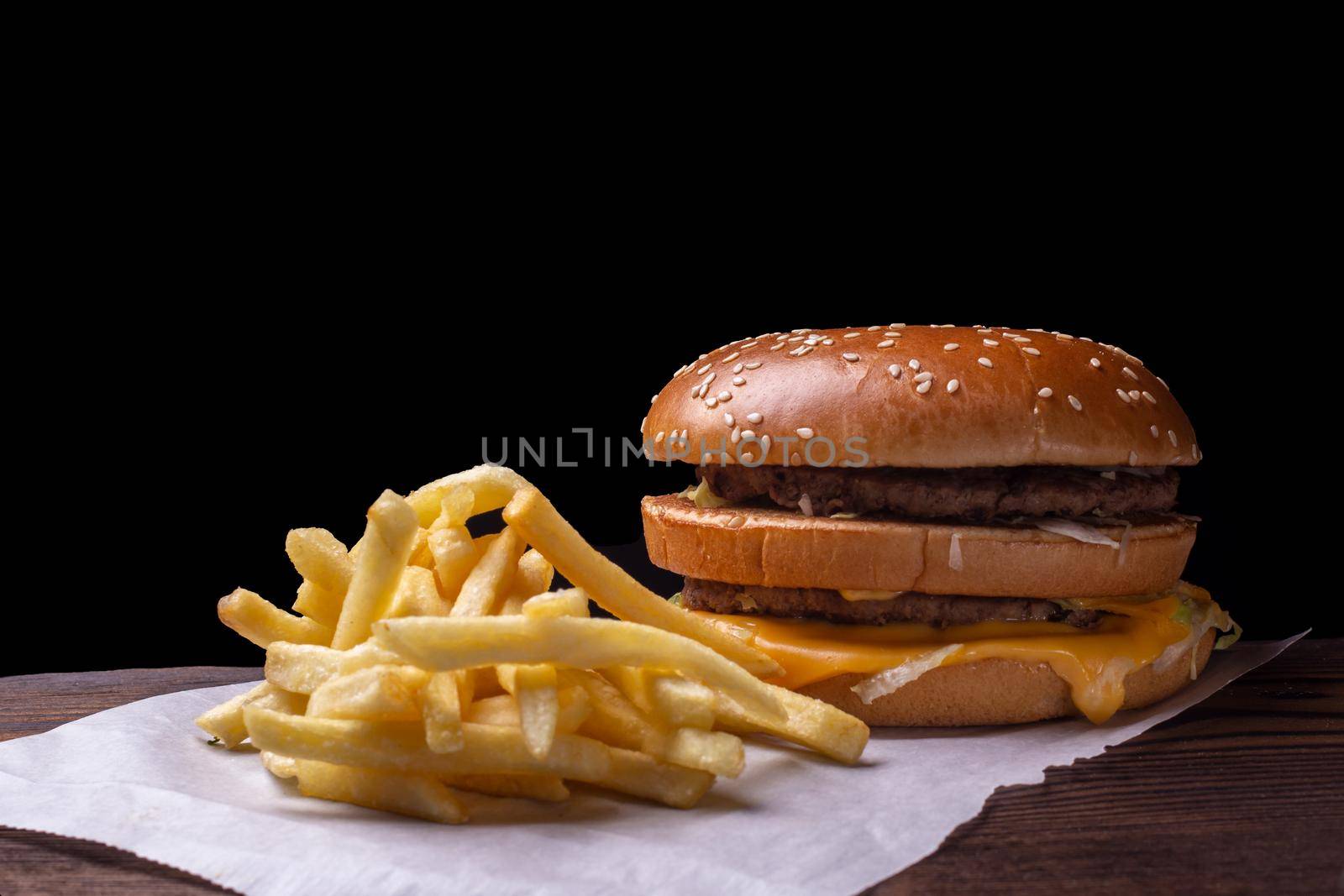 Hamburger, details of two gourmet double burgers, cheese, tomato, bacon, lettuce, onion. on wooden surface, abstract background selective focus