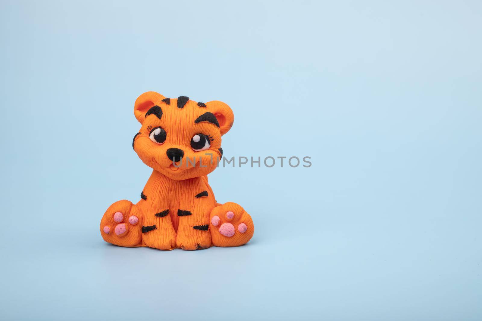 A hand-sculpted orange tiger figurine on a blue background. The year 2022 is the year of the tiger according to the Eastern calendar.