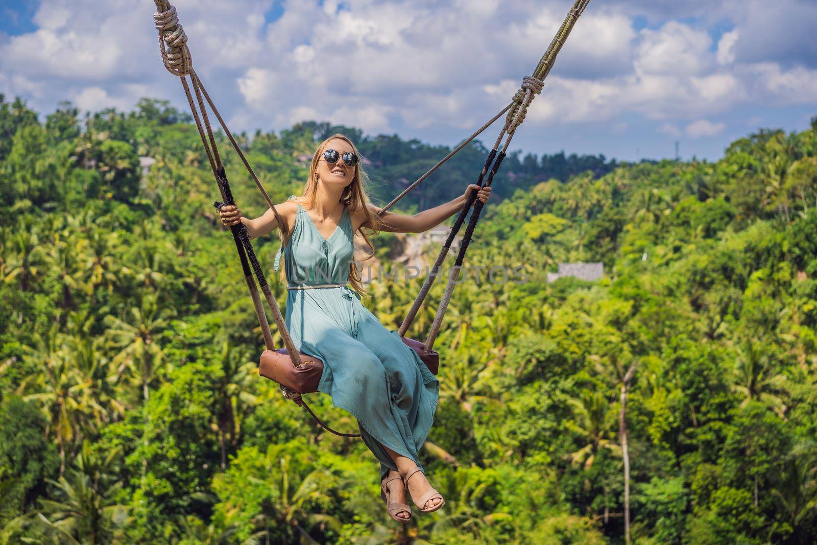 Young woman swinging in the jungle rainforest of Bali island, Indonesia. Swing in the tropics. Swings - trend of Bali.