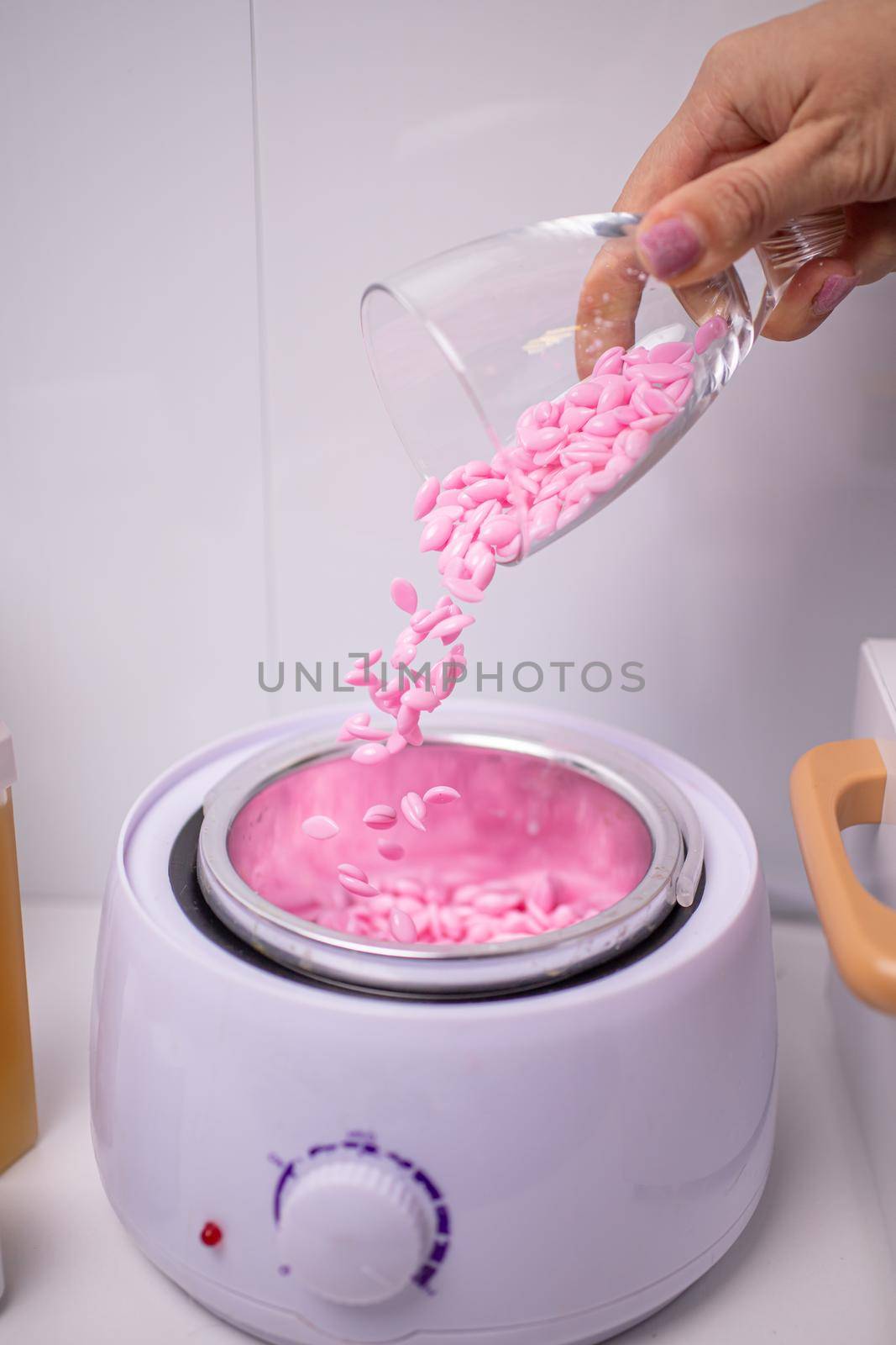 preparation of wax for work. from a glass glass in the hand, wax granules are poured into the heating device