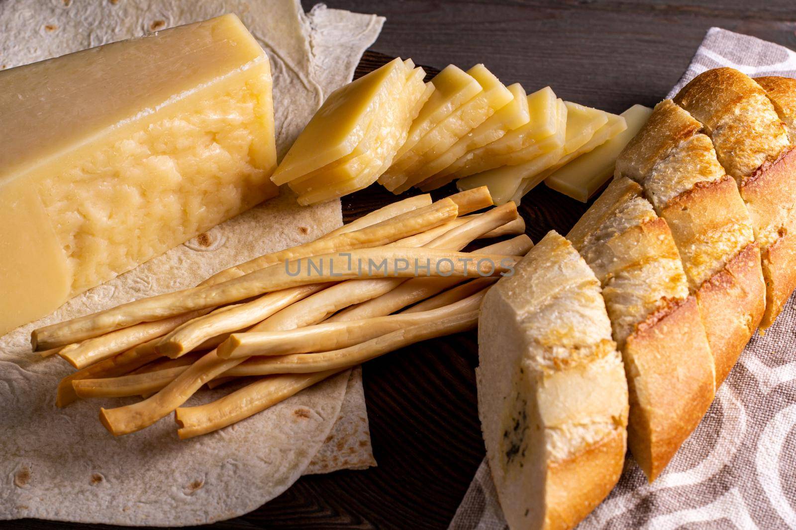 hard cheese and fibrous cheese with slices of bread are cut on a wooden board