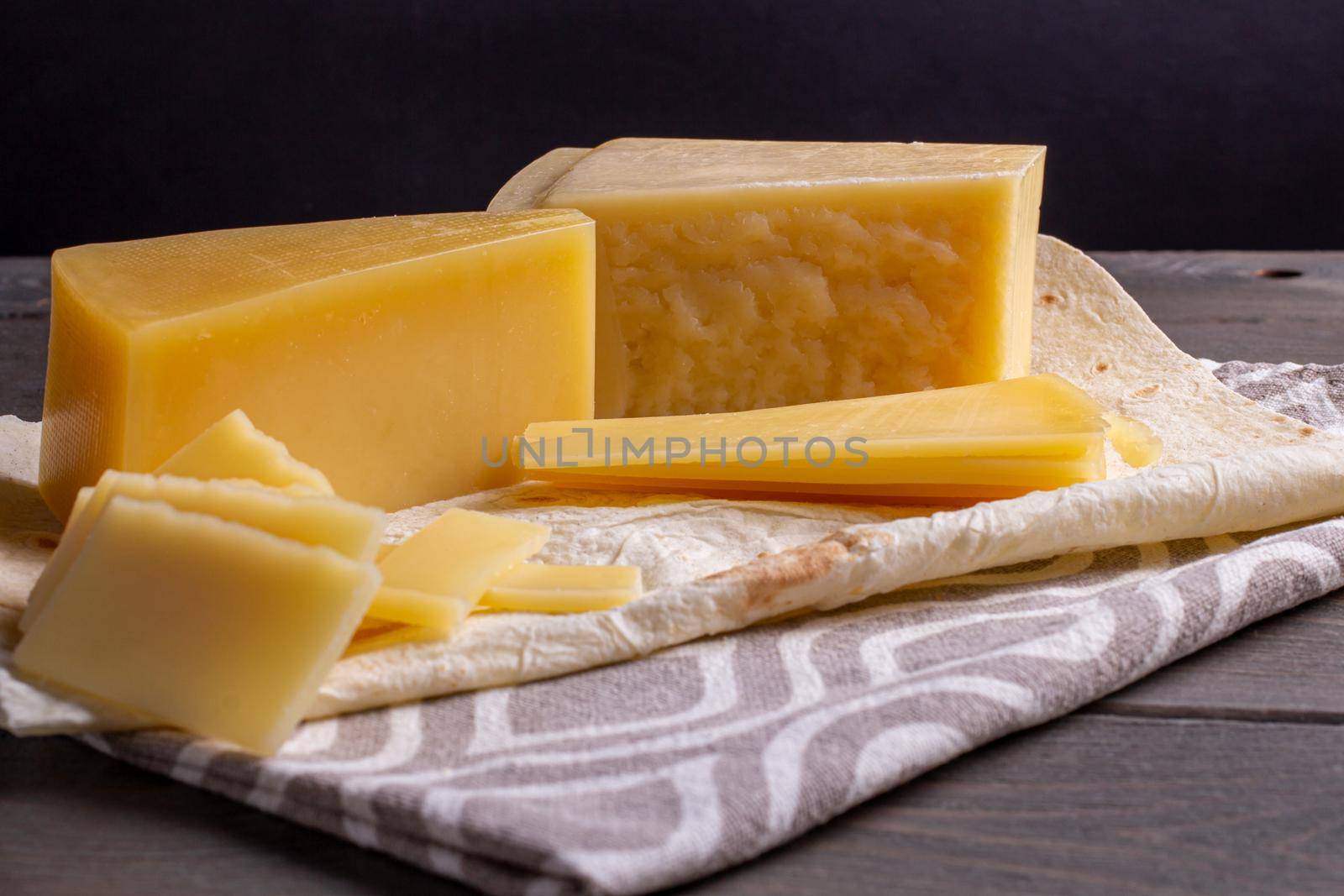 hard cheese and fibrous cheese with slices of bread are cut on a wooden board