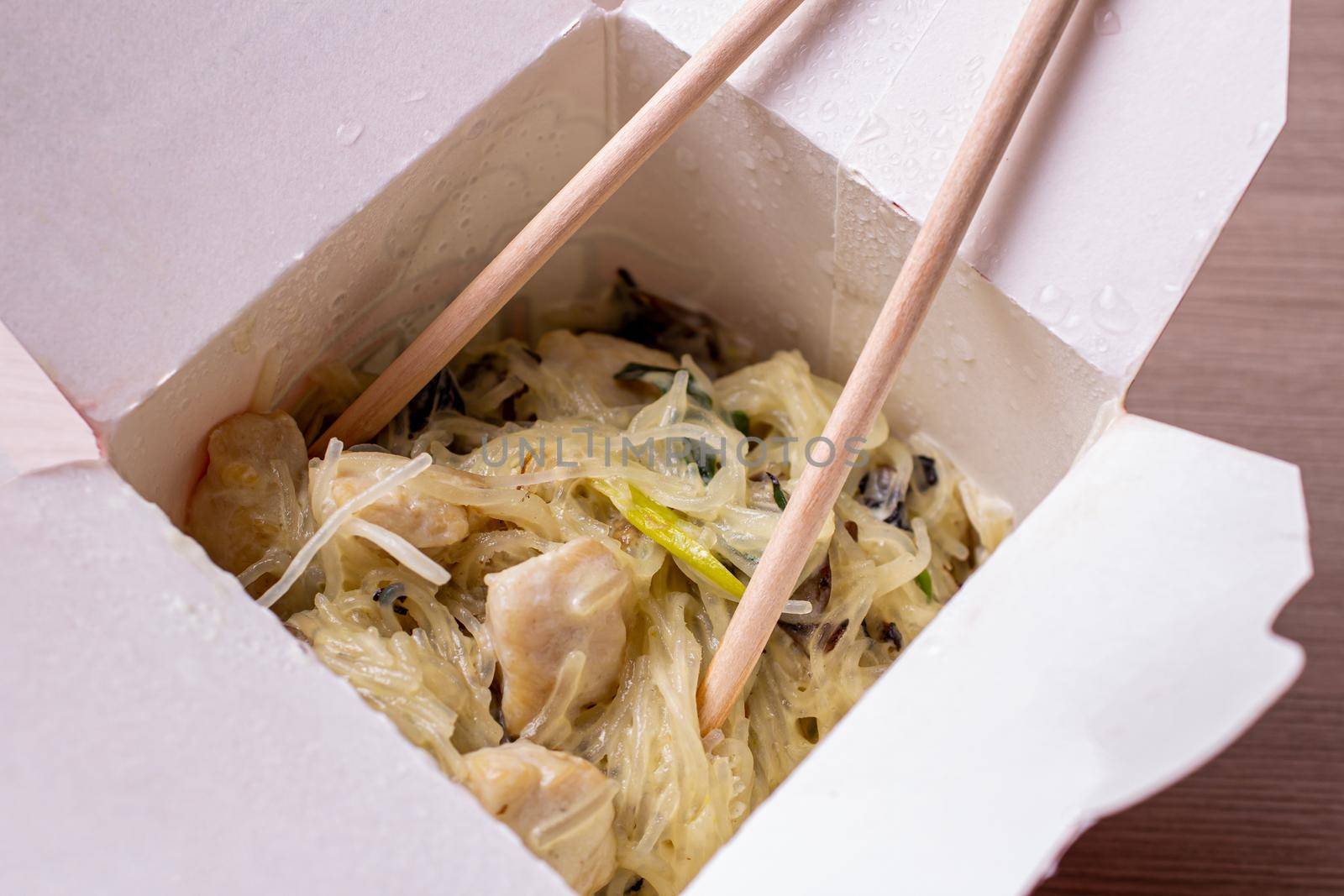 Chinese food egg noodles in cream sauce close-up. Open paper box