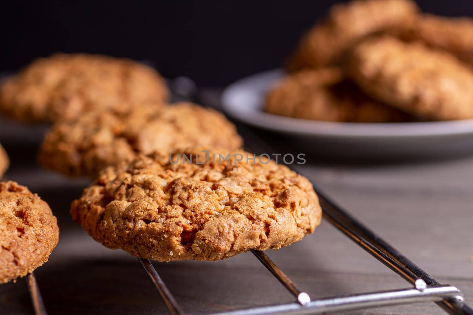 Close-up of a freshly baked stack of warm oatmeal cookies on a cooling rack on a dark background. the view side