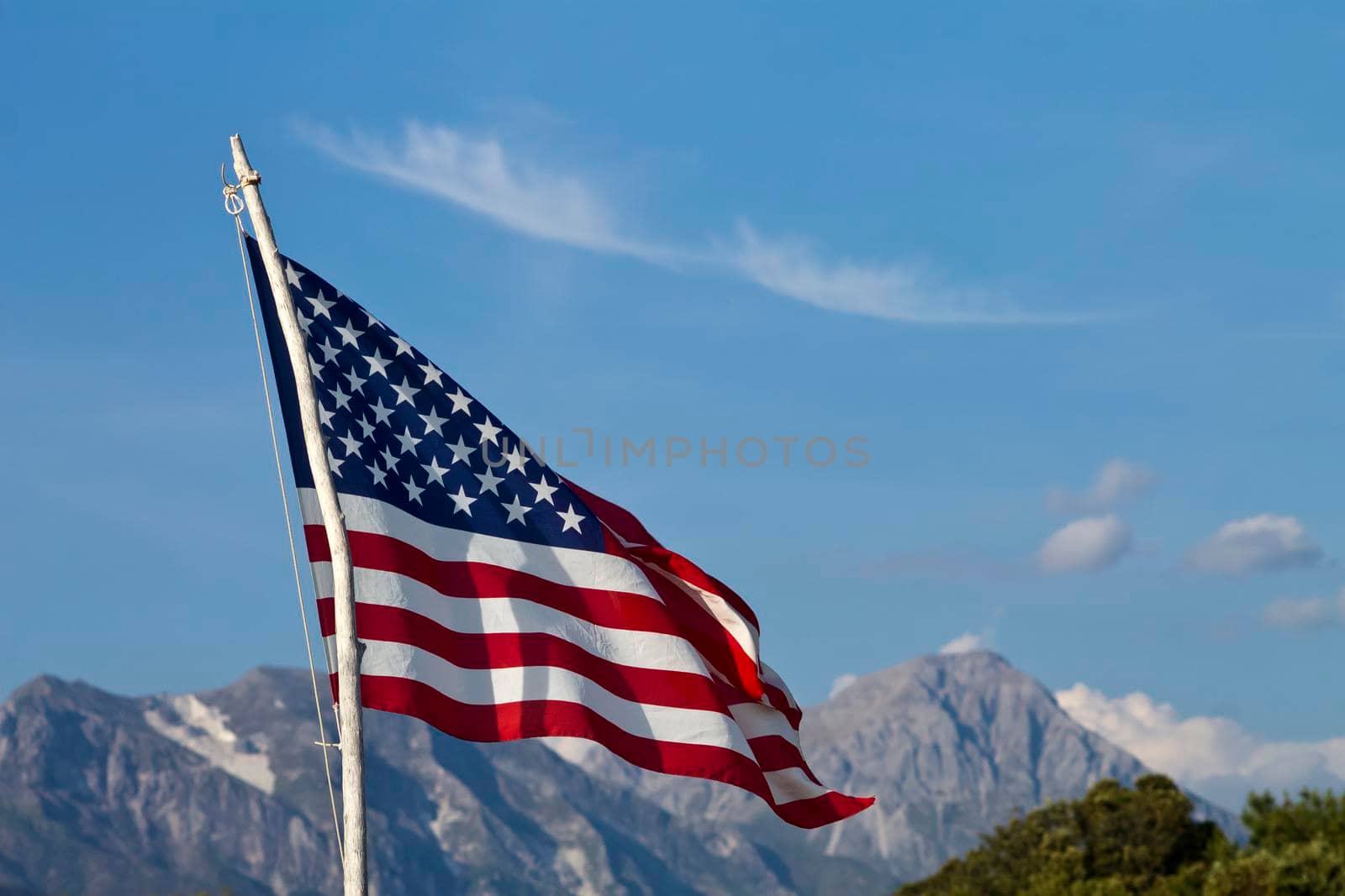 American flag waving in a sunny day with mountains in background