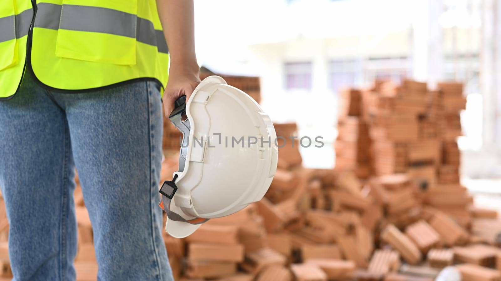 Unrecognized engineer with helmet in hand and standing at construction site. Industry, Engineer, construction concept.