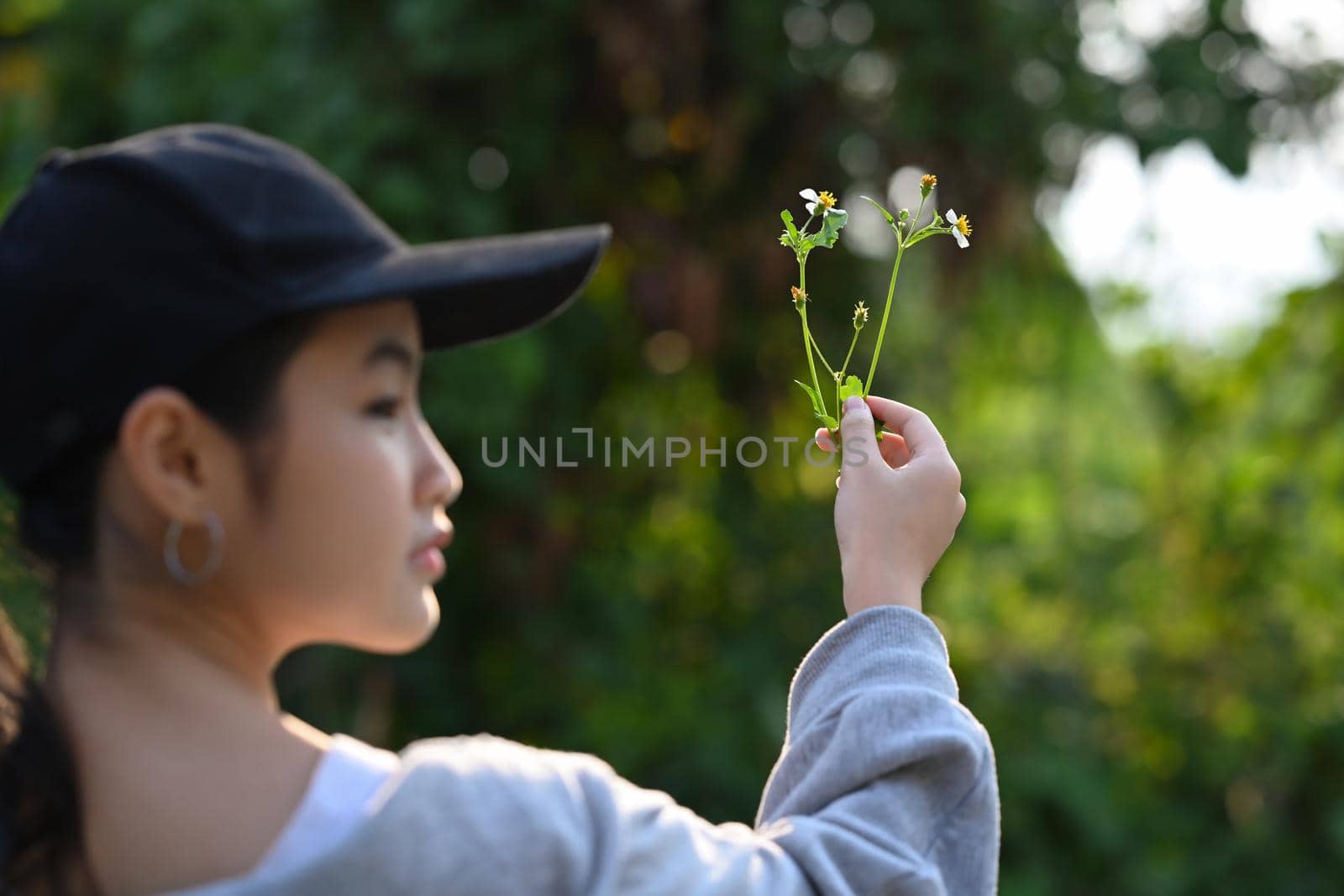 Back view of asian girl hand holding young plant on blur green nature background. Earth day concept.