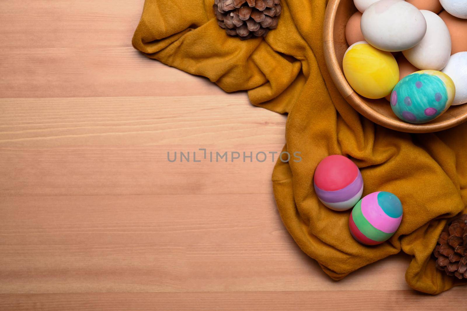 Above view Easter basket filled with painted Easter eggs over wooden background.