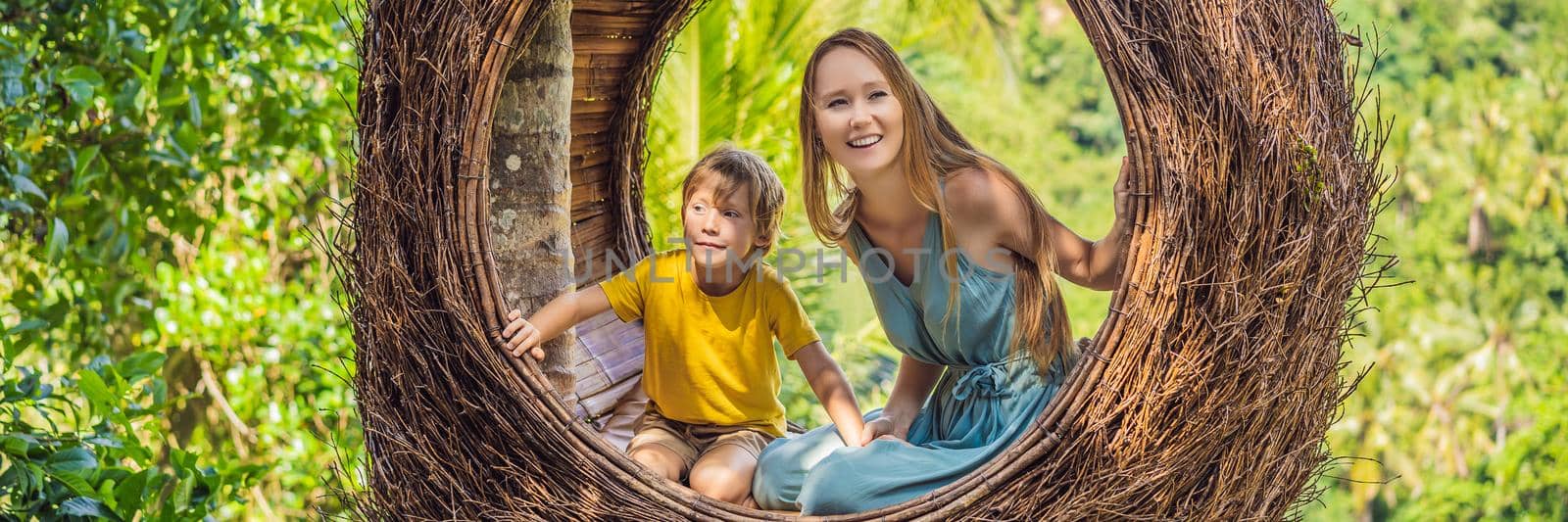 BANNER, LONG FORMAT Bali trend, straw nests everywhere. Happy family enjoying their travel around Bali island, Indonesia. Making a stop on a beautiful hill. Photo in a straw nest, natural environment. Lifestyle. Traveling with kids concept. What to do with children. Child friendly place.