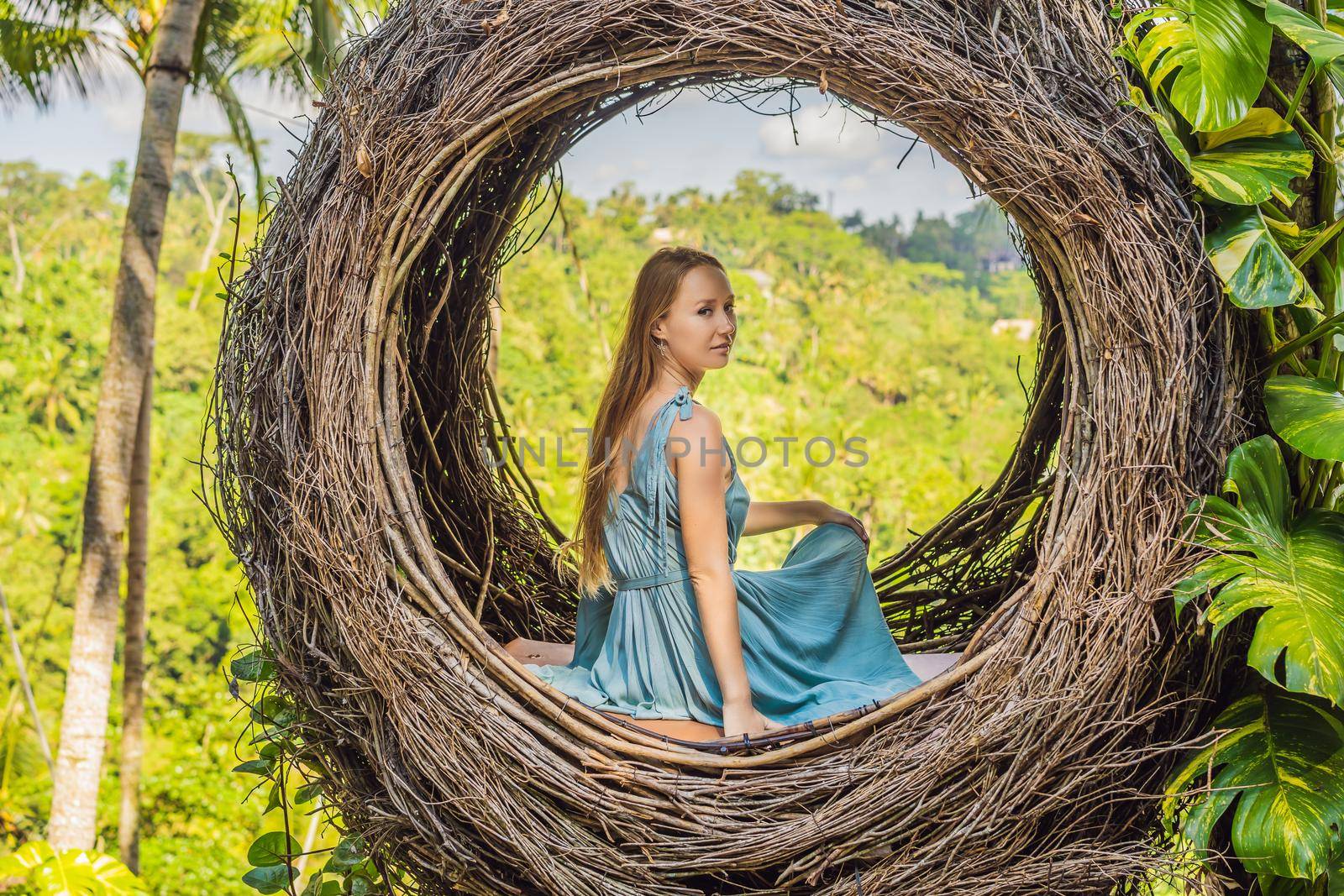 Bali trend, straw nests everywhere. Young tourist enjoying her travel around Bali island, Indonesia. Making a stop on a beautiful hill. Photo in a straw nest, natural environment. Lifestyle.