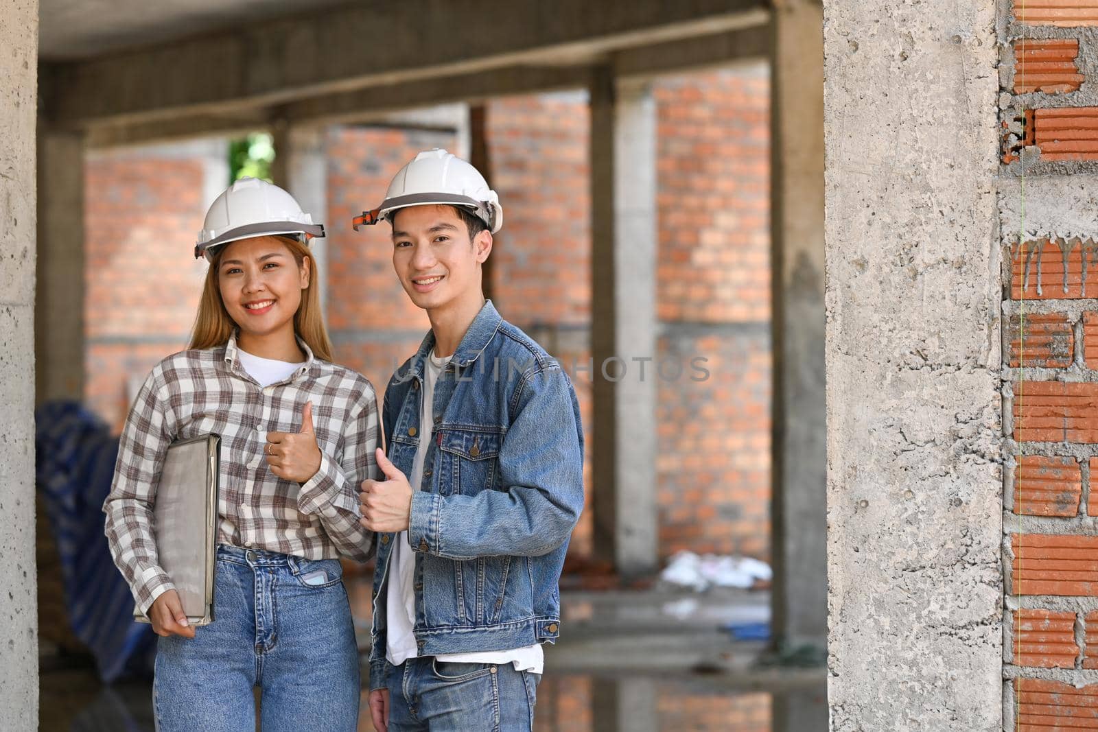 Two young engineers wearing safety helmet standing construction site. Industry, Engineer, construction concept.