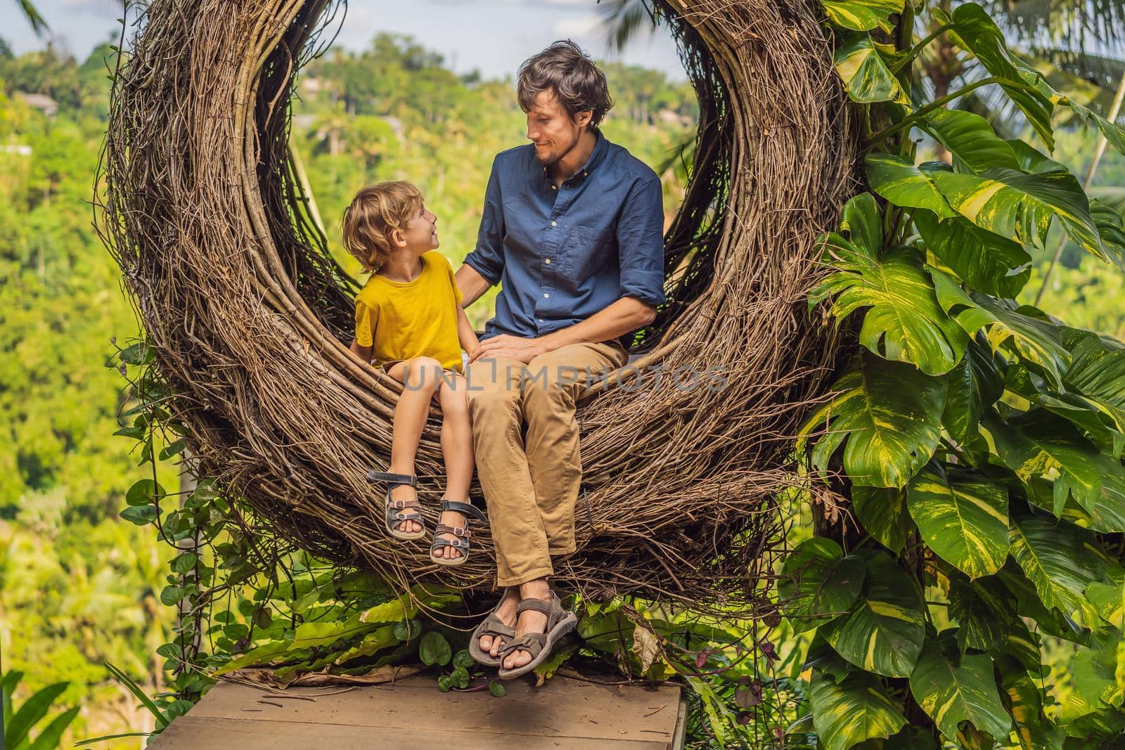 Bali trend, straw nests everywhere. Child friendly place. Happy family enjoying their travel around Bali island, Indonesia. Making a stop on a beautiful hill. Photo in a straw nest, natural environment. Lifestyle. Traveling with kids concept. What to do with children by galitskaya