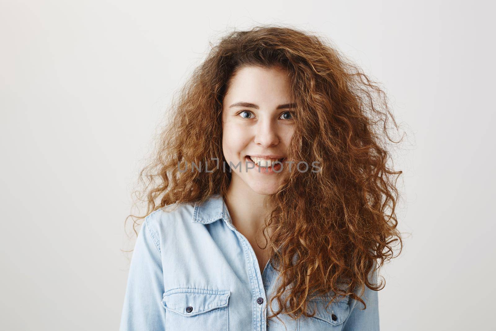 Portrait beautiful woman face close up portrait young curly hair studio on gray.