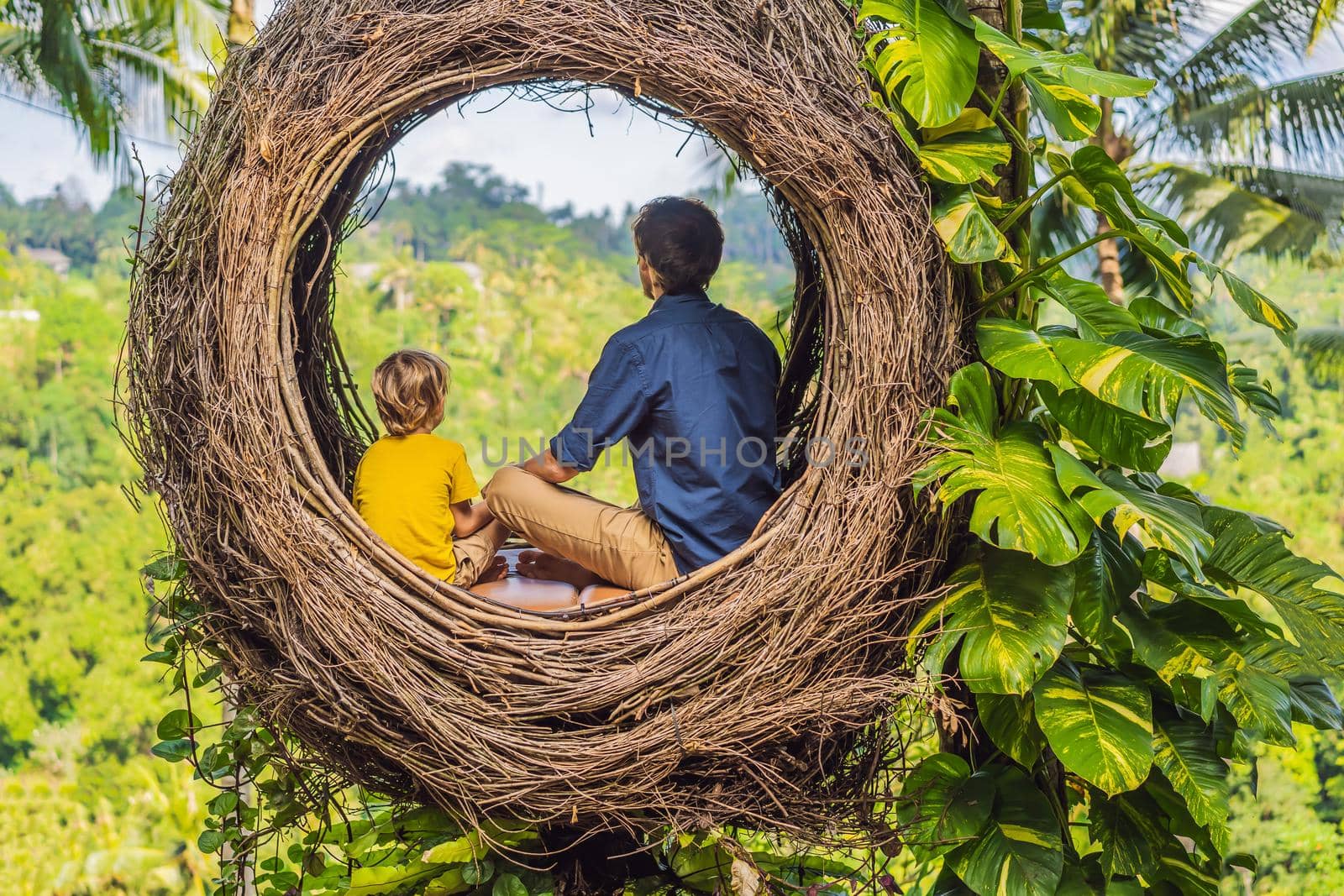 Bali trend, straw nests everywhere. Child friendly place. Happy family enjoying their travel around Bali island, Indonesia. Making a stop on a beautiful hill. Photo in a straw nest, natural environment. Lifestyle. Traveling with kids concept. What to do with children by galitskaya