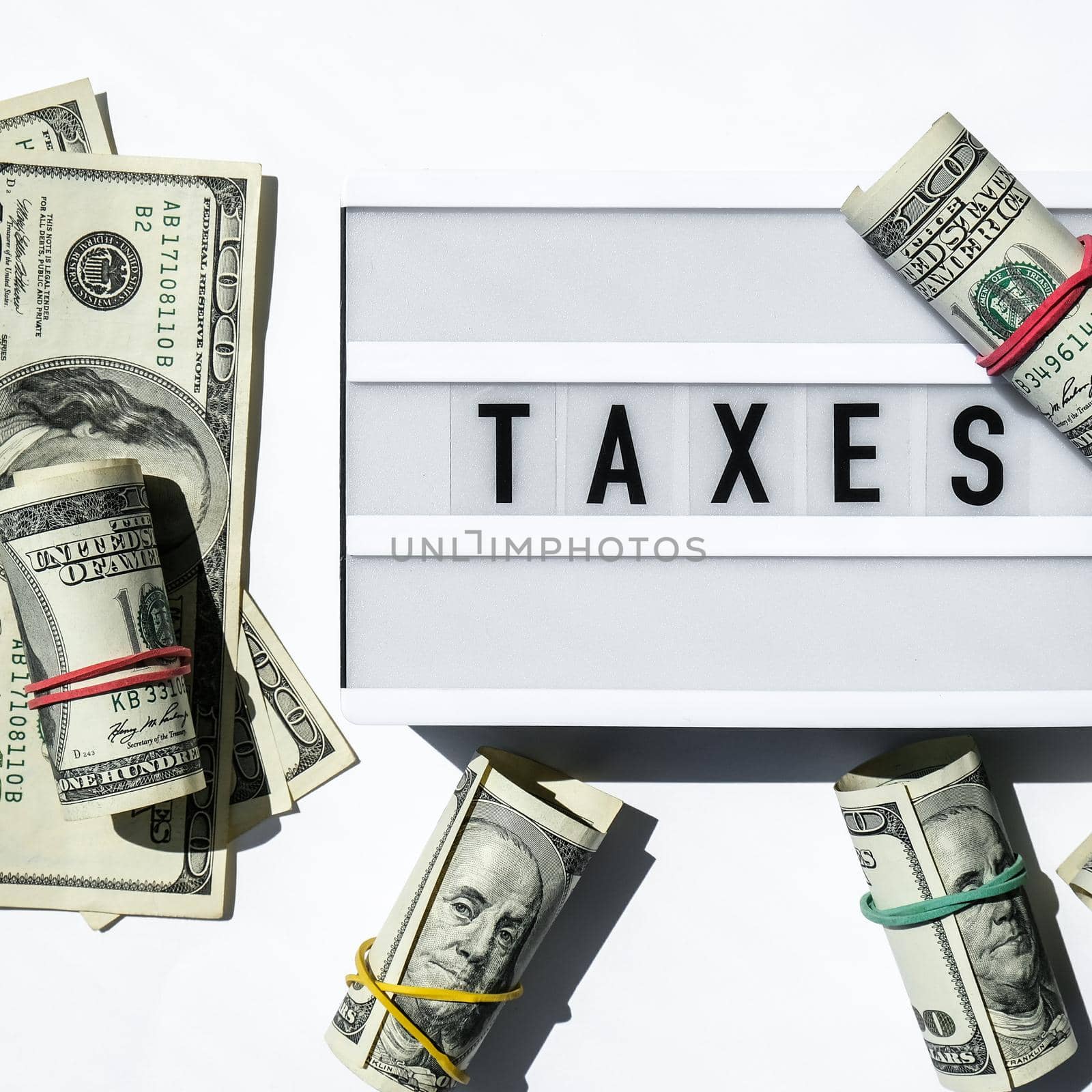 Lightbox board with word TAXES in black letters around Us dollars banknotes. Tax payment and filing concept. Money, Business, finance, investment, saving and corruption. Cash bill