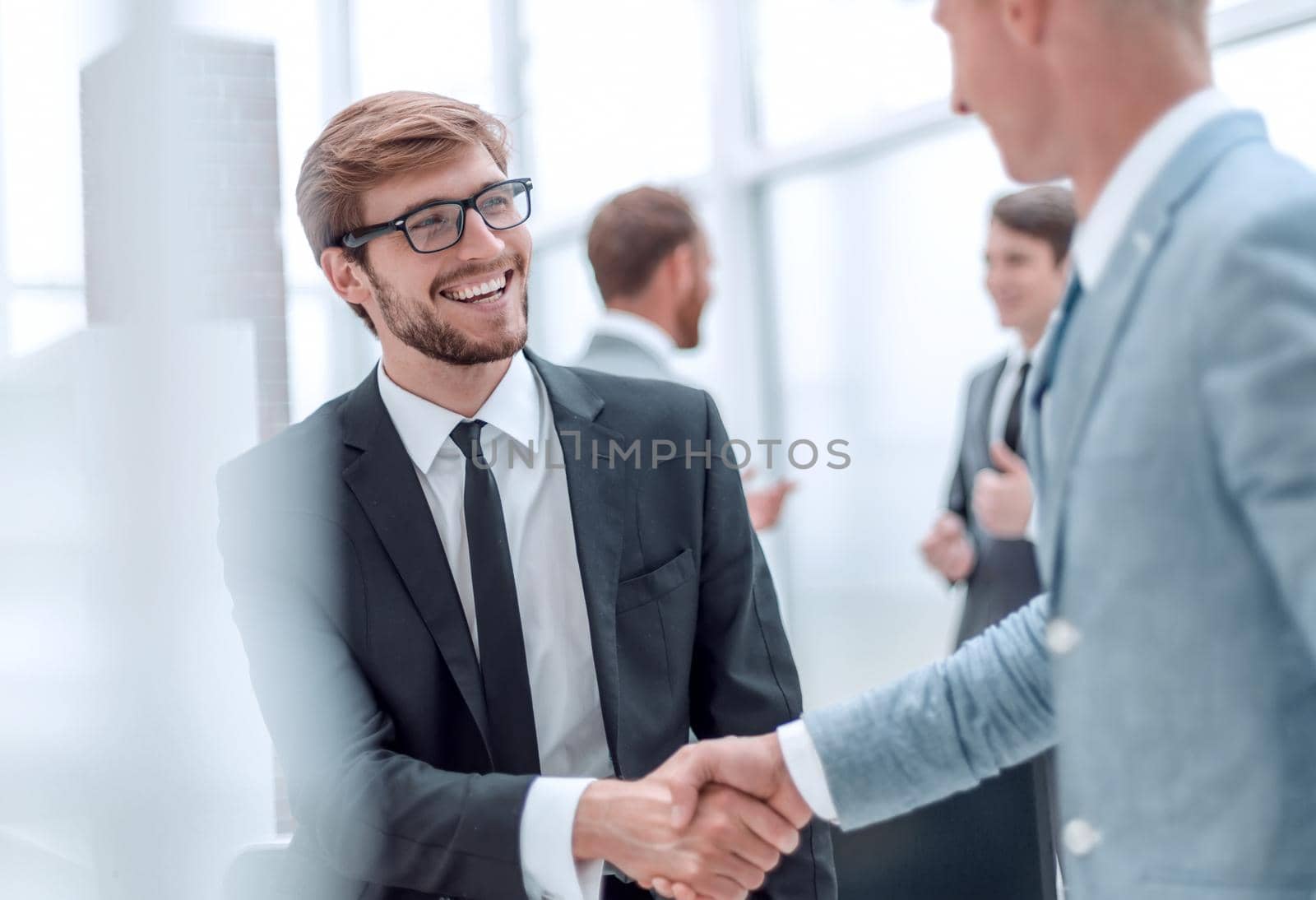 smiling businessman shaking hands with his business partner by asdf