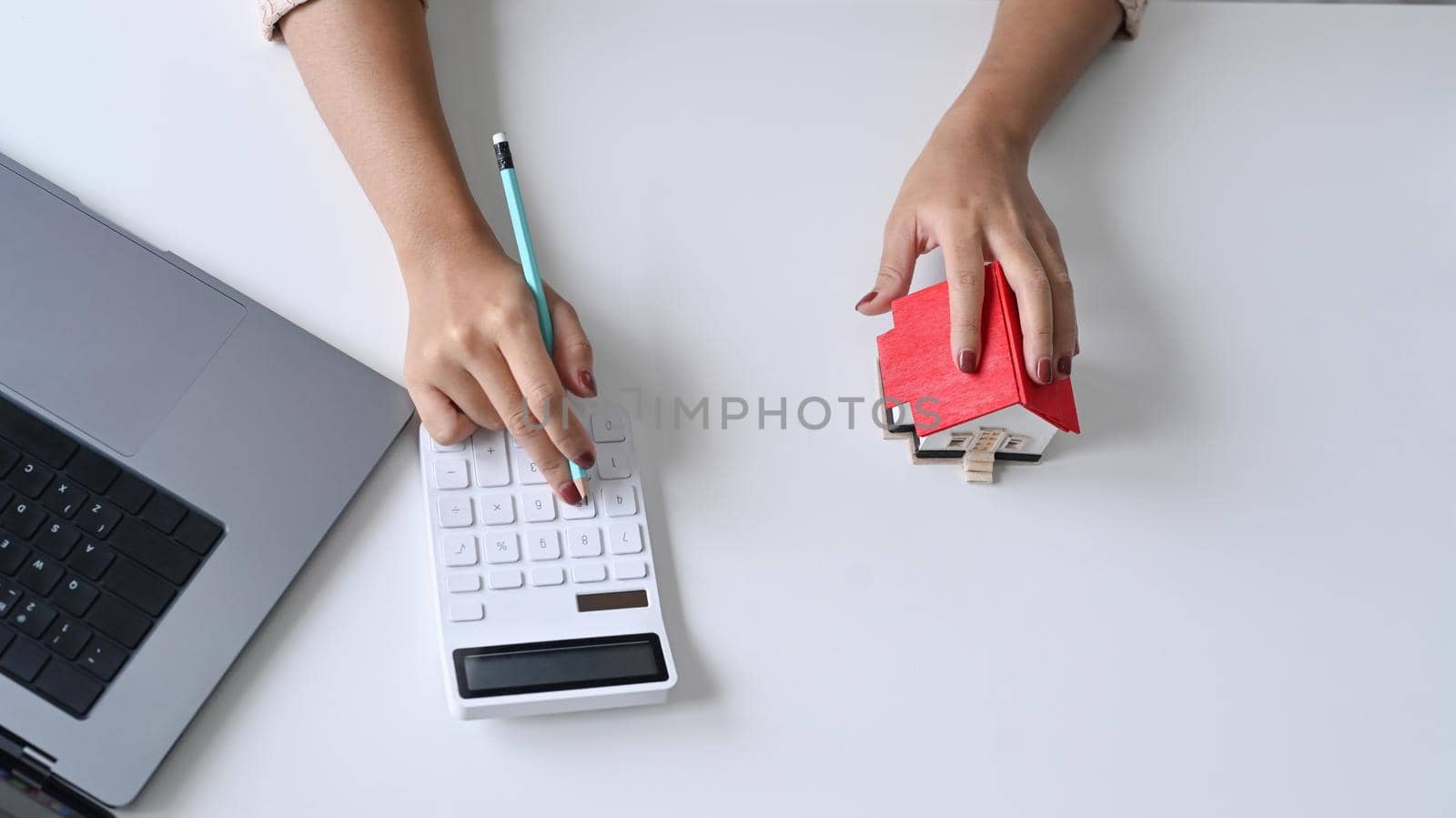 Overhead view real estate agent using calculator on white office desk. Real estate investment and insurance concept.