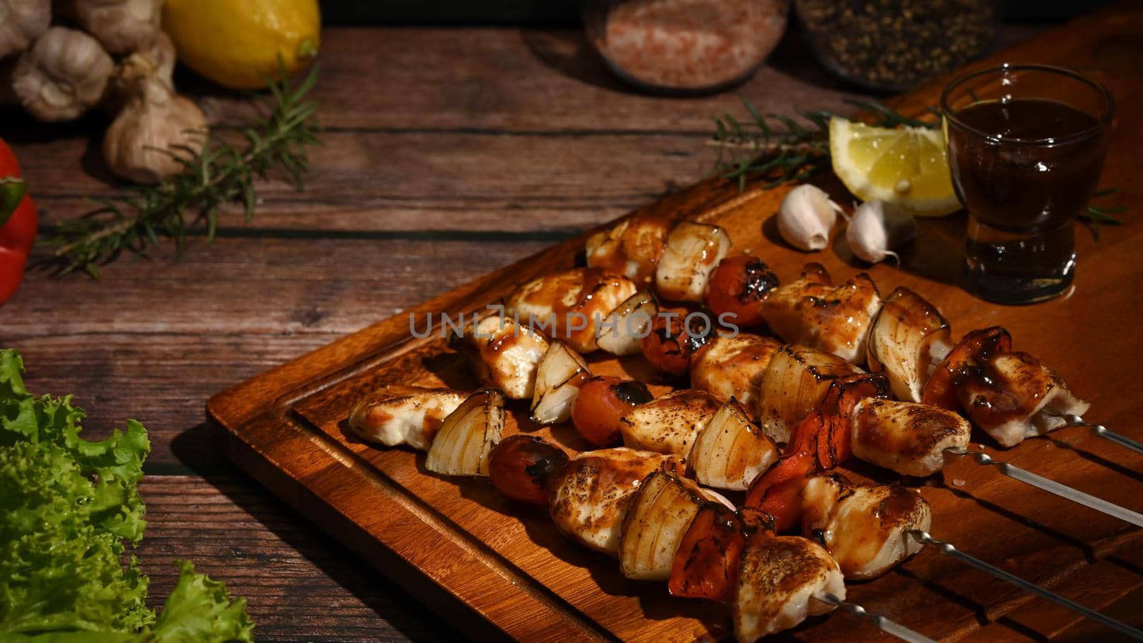Grilled chicken kebab with cherry tomato, sweet pepper and onions on wooden plate. BBQ, food, party concept.