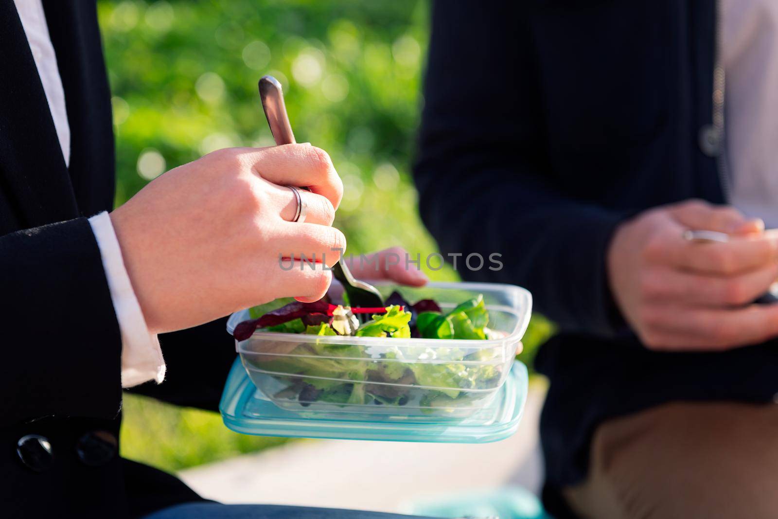 detail of the hands of an unrecognizable woman eating a salad in a park during a work break, concept of healthy fast food at work, copy space for text