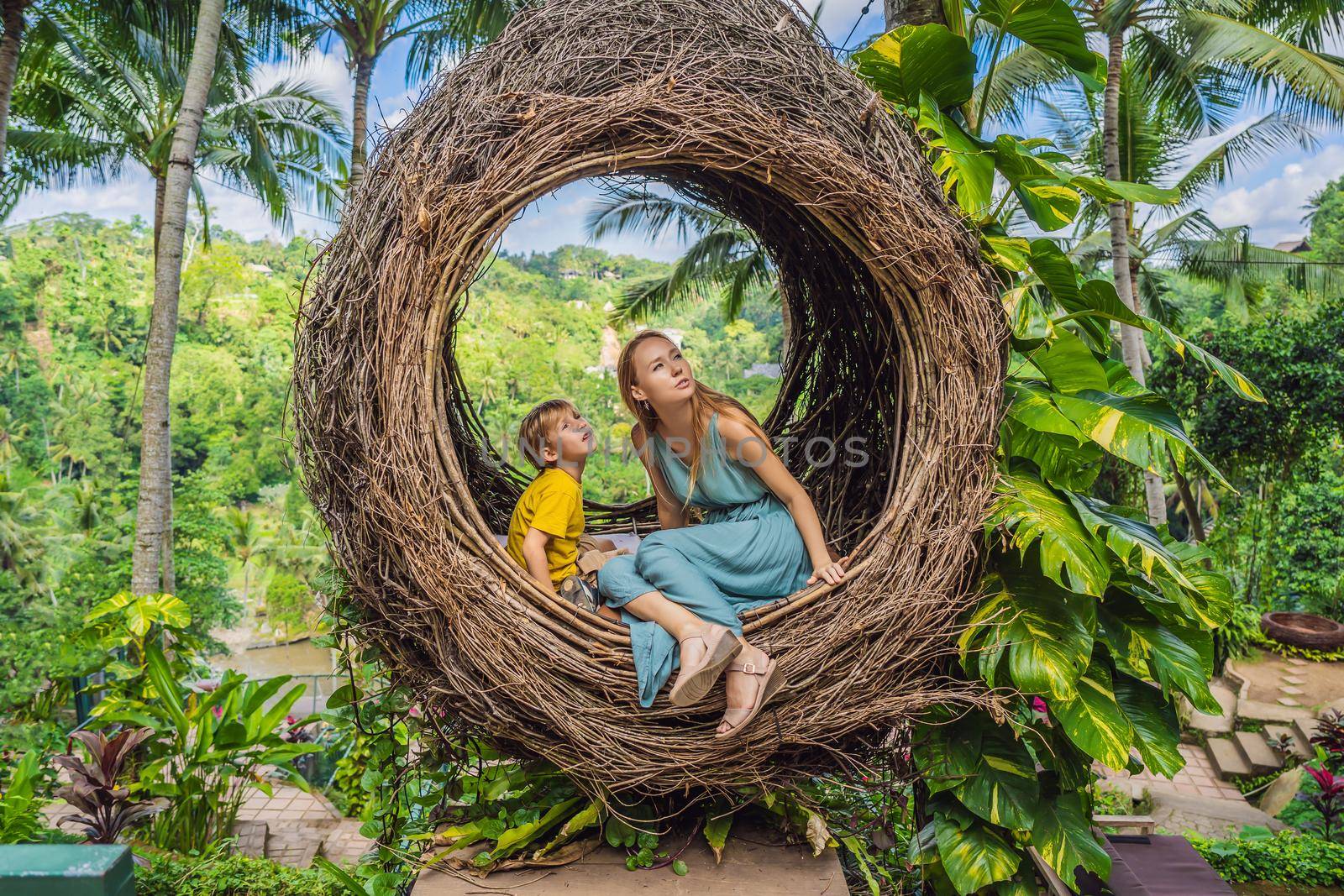 Bali trend, straw nests everywhere. Happy family enjoying their travel around Bali island, Indonesia. Making a stop on a beautiful hill. Photo in a straw nest, natural environment. Lifestyle. Traveling with kids concept. What to do with children. Child friendly place by galitskaya