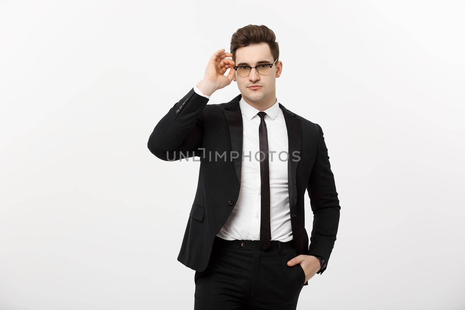 Business Concept: Young handsome businessman wearing glasses holding hand in pocket isolated on white background