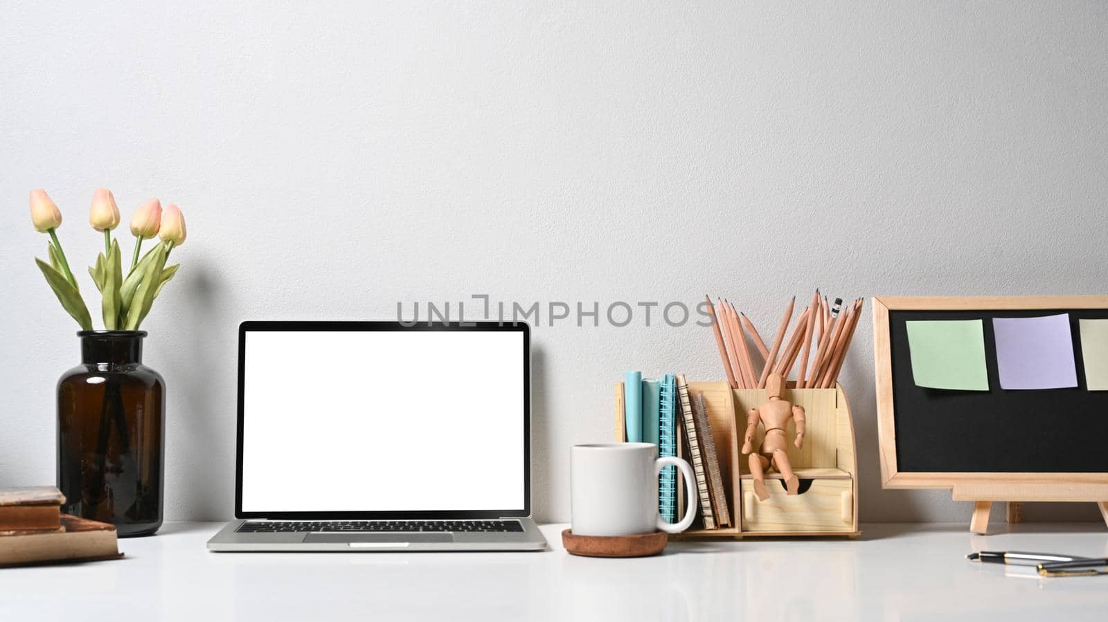 Creative designer workplace with laptop computer, flower pot, coffee cup and stationery on white table.