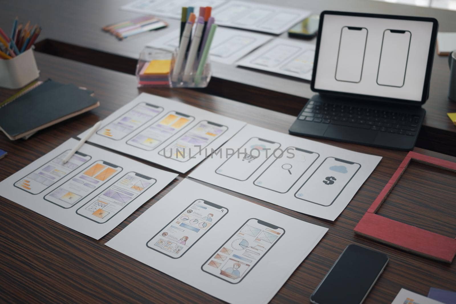 Digital tablet and wireframe sketches for mobile application on wooden table at creative office.