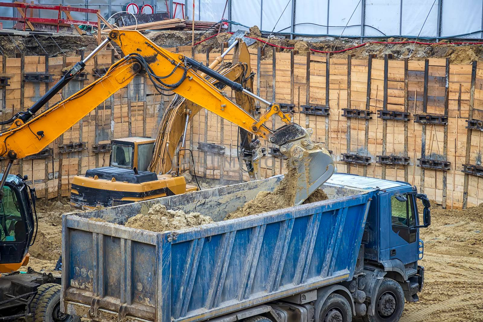 Excavator is loading excavation on the truck. Heavy construction equipment working at the construction site.
