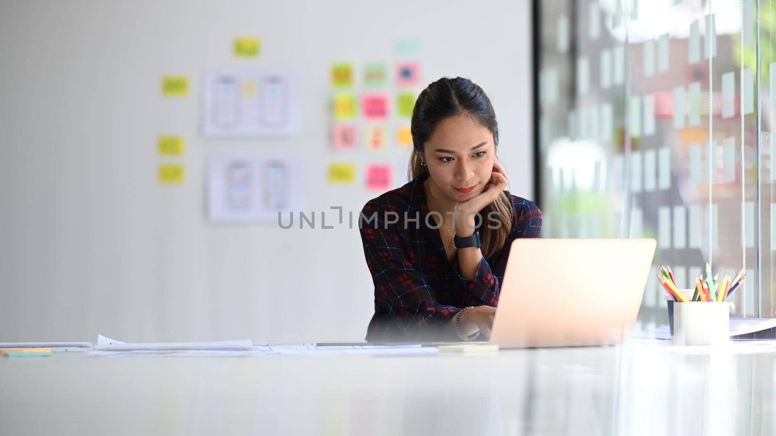 Concentrated female web developer working on mobile application software design project at modern workplace.