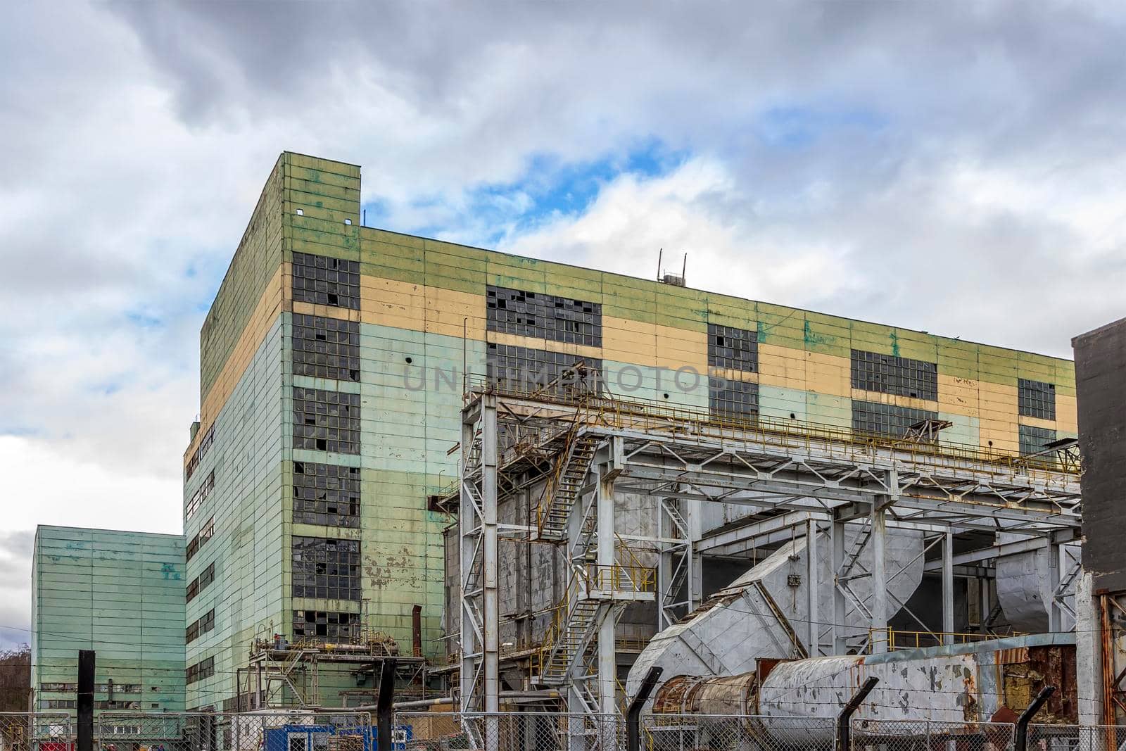 Multi Story production building behind a wire fence. Picturesque old factory. Aged industrial object.  by EdVal