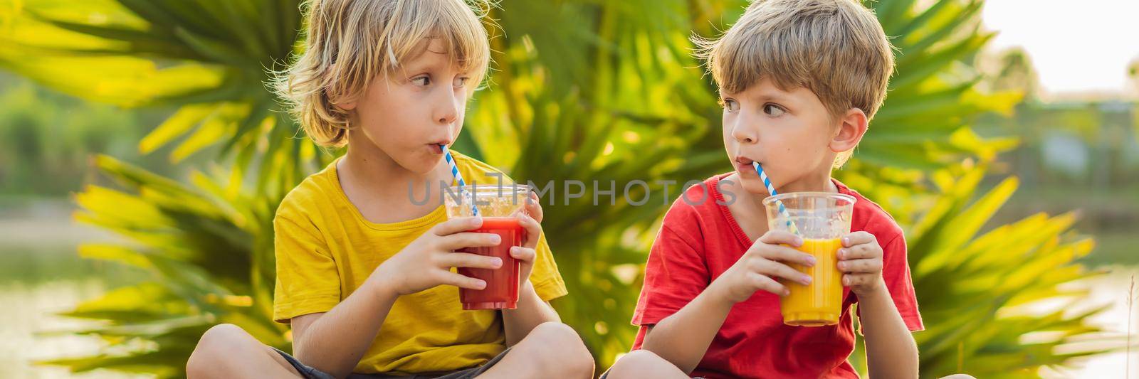 BANNER, LONG FORMAT Two boys drink healthy smoothies against the backdrop of palm trees. Mango and watermelon smoothies. Healthy nutrition and vitamins for children.