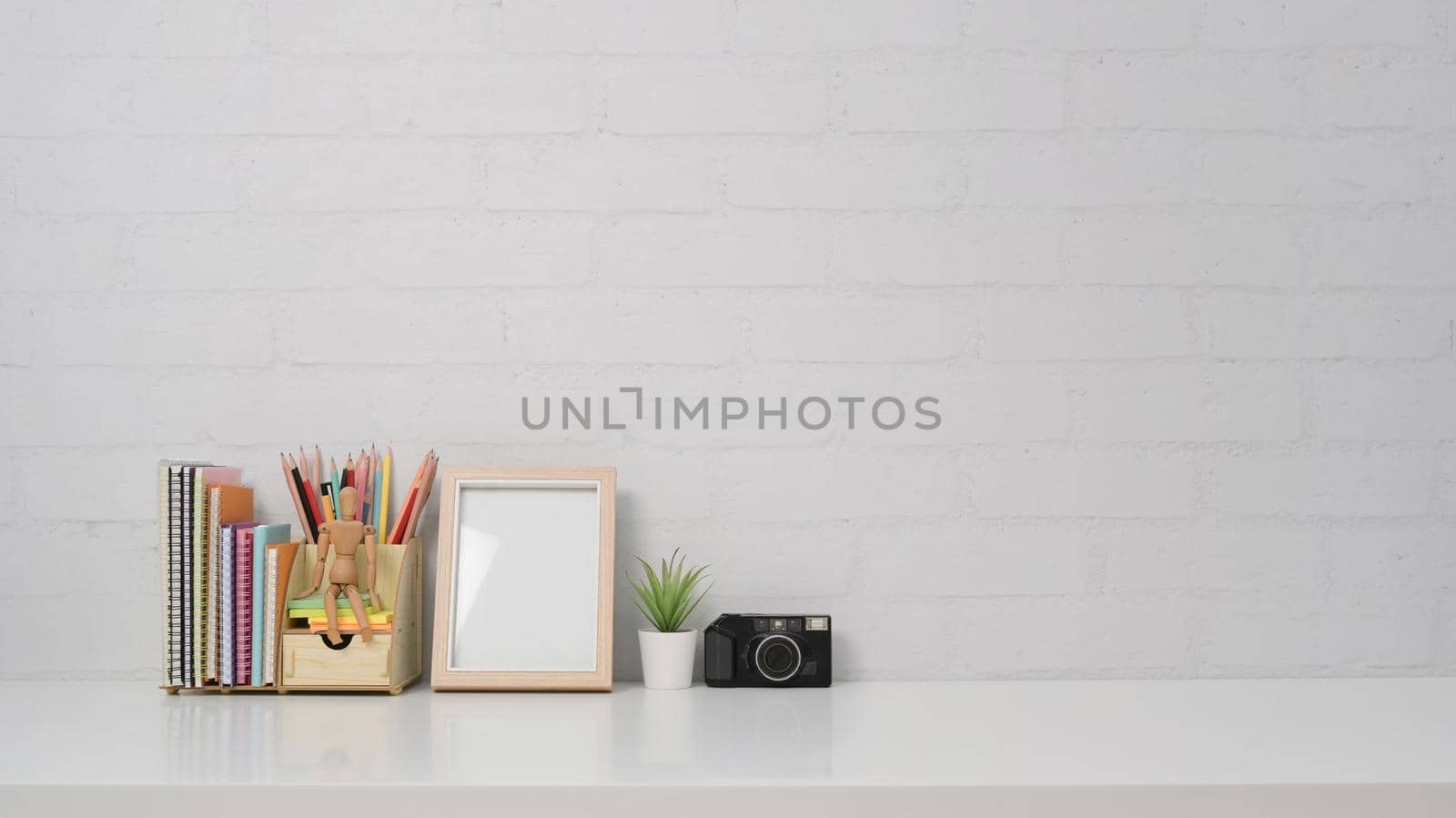Creative workplace with empty frame, camera and stationery on white table with copy space.