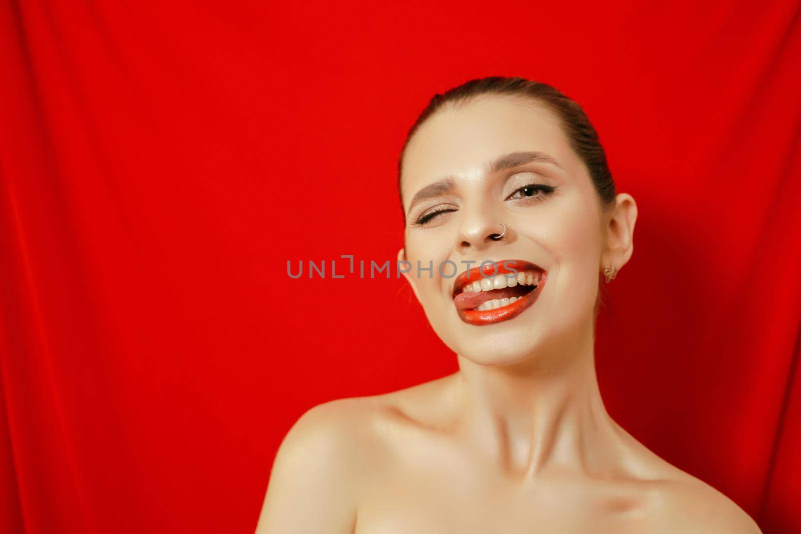 Portrait of a smiling beautiful young woman. Red background. Studio shot. by Matiunina