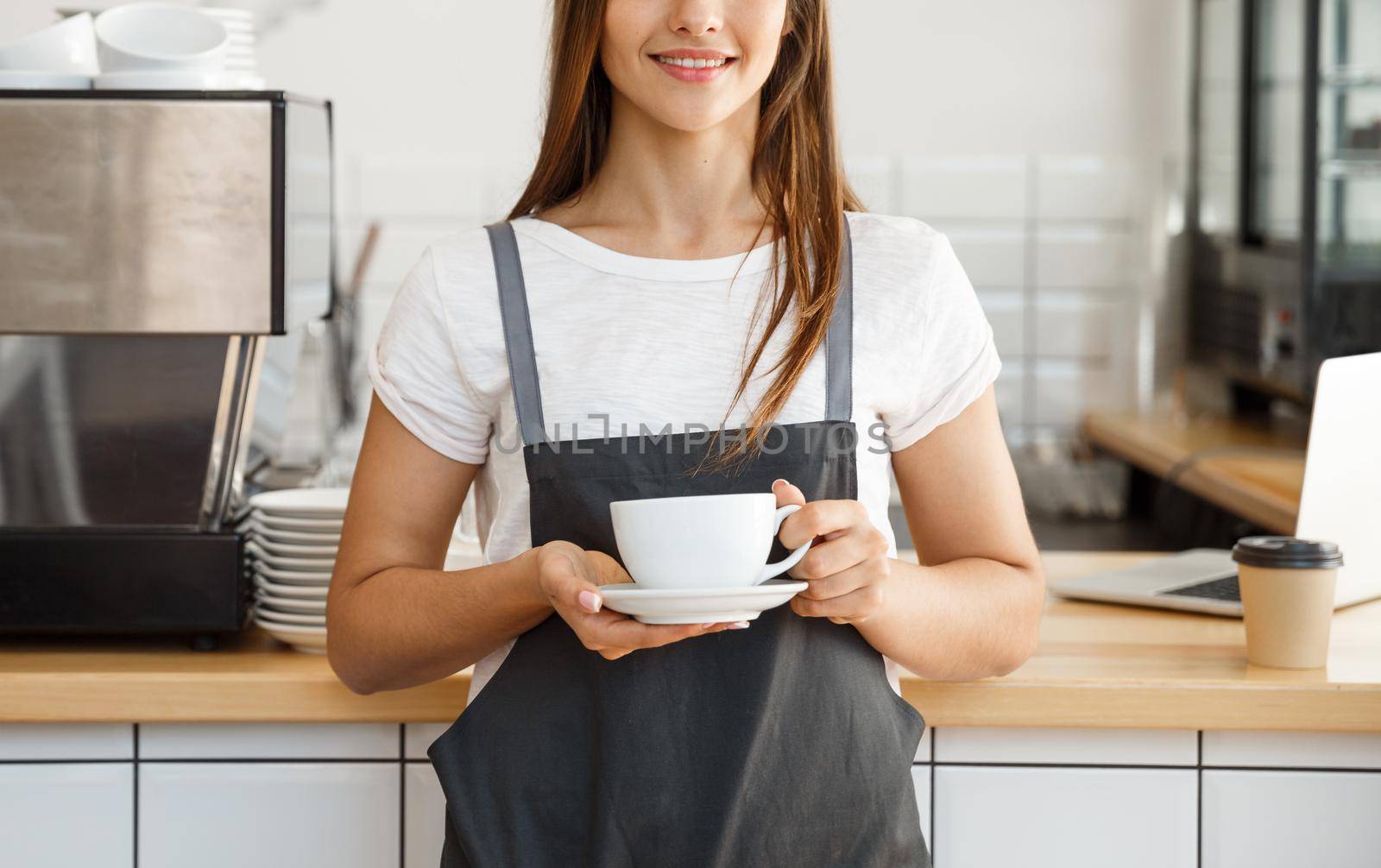 Coffee Business Concept - Caucasian female serving coffee while standing in coffee shop. Focus on female hands placing a cup of coffee.