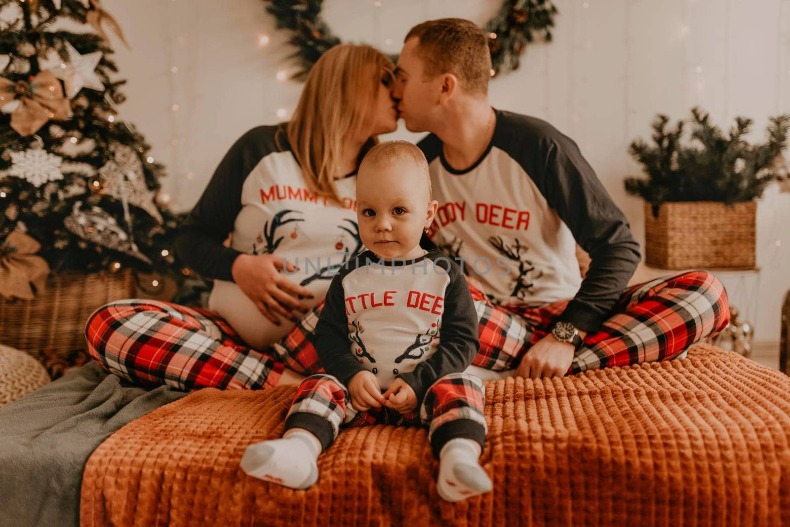 cheerful happy family in pajamas with a child kissing on the bed in the bedroom. new year family clothes looks outfits. Valentine's Day Celebration Gifts