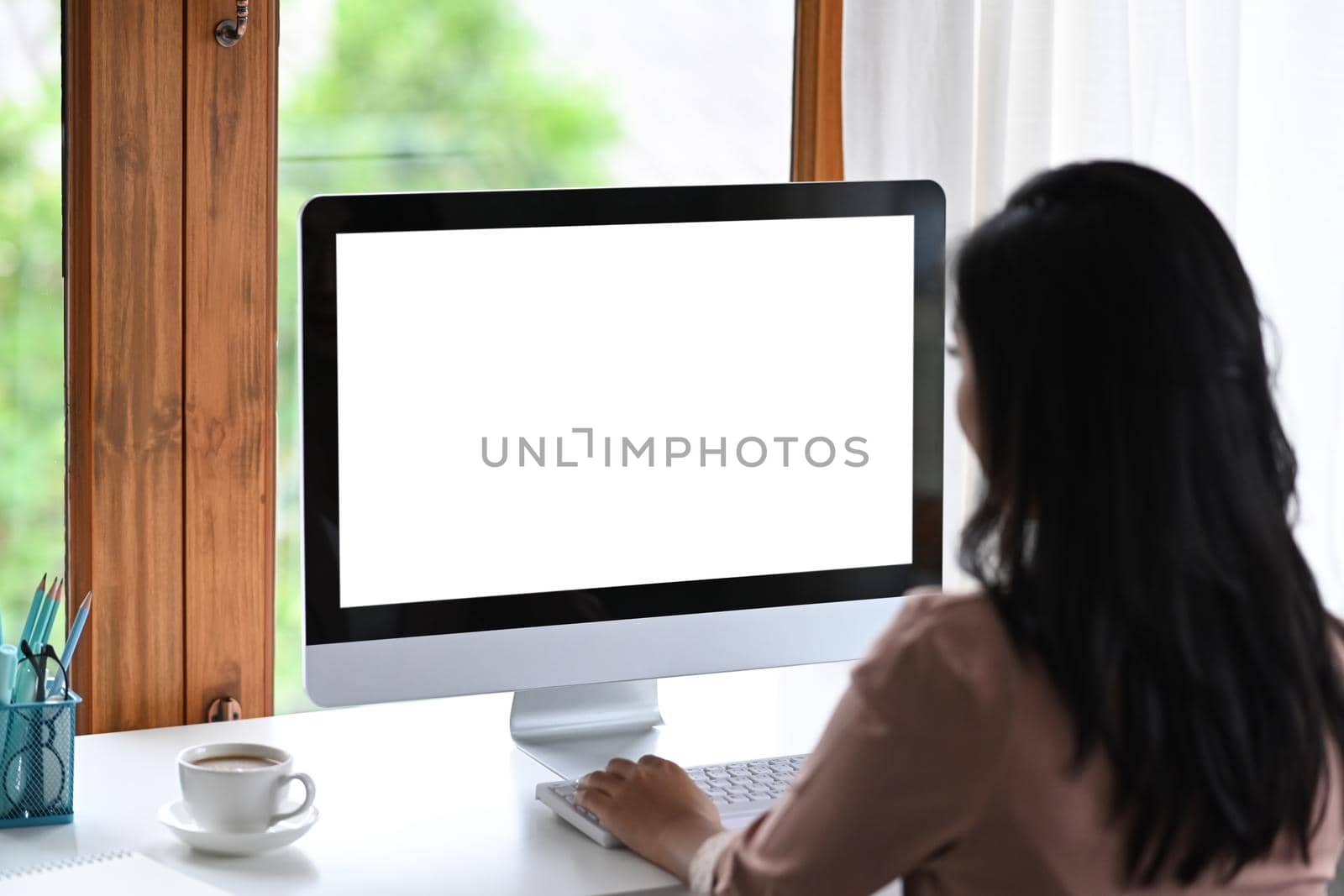 Rear view of creative woman working with modern computer at her workplace.