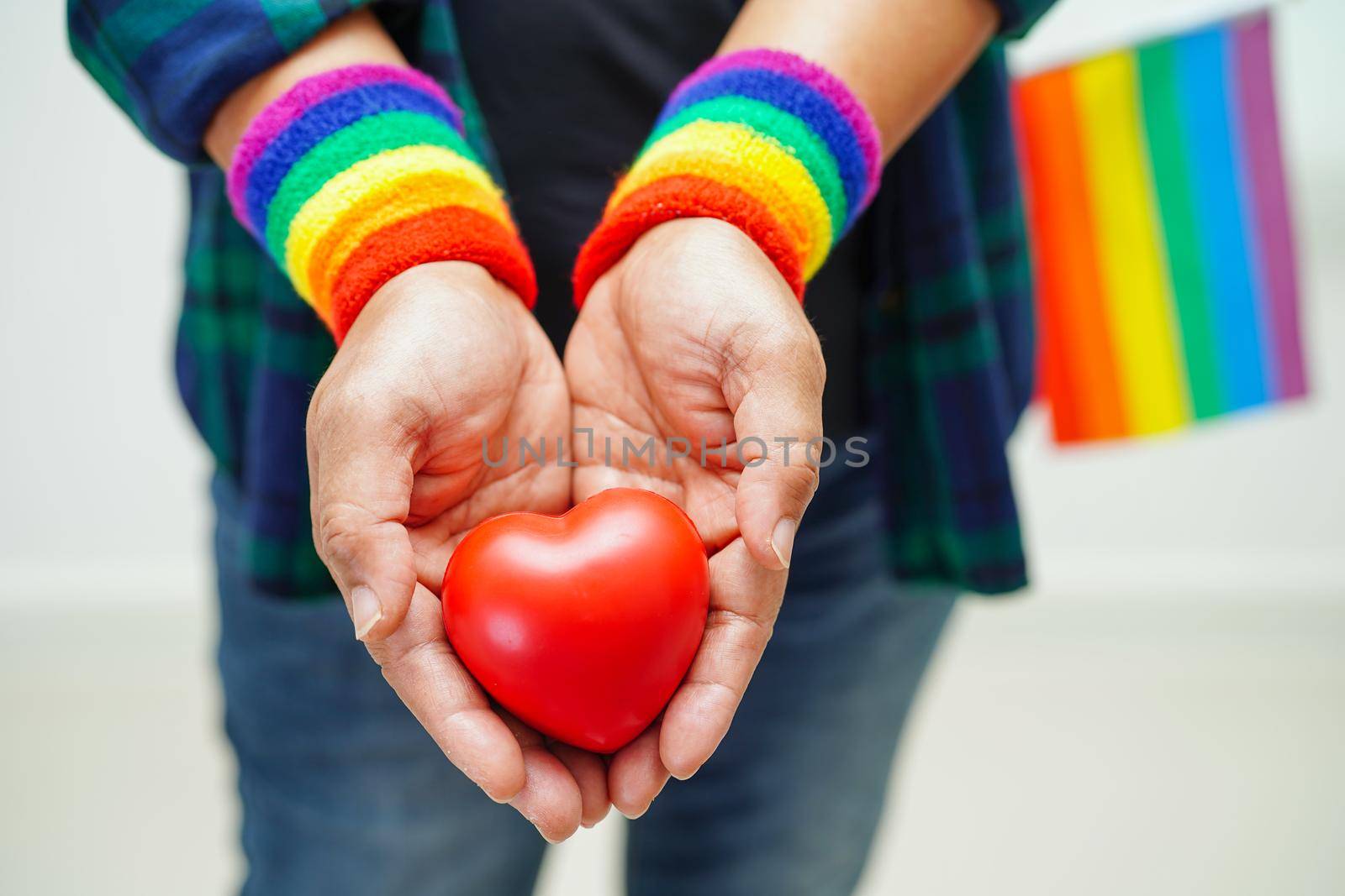 Asian woman holding red hert with rainbow flag, LGBT symbol rights and gender equality, LGBT Pride Month in June.