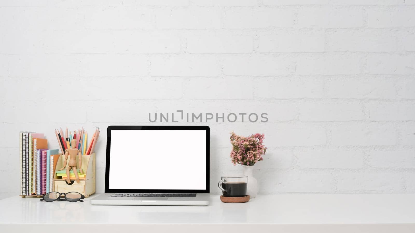 Laptop computer, coffee cup, stationery and flower pot on white table with copy space.