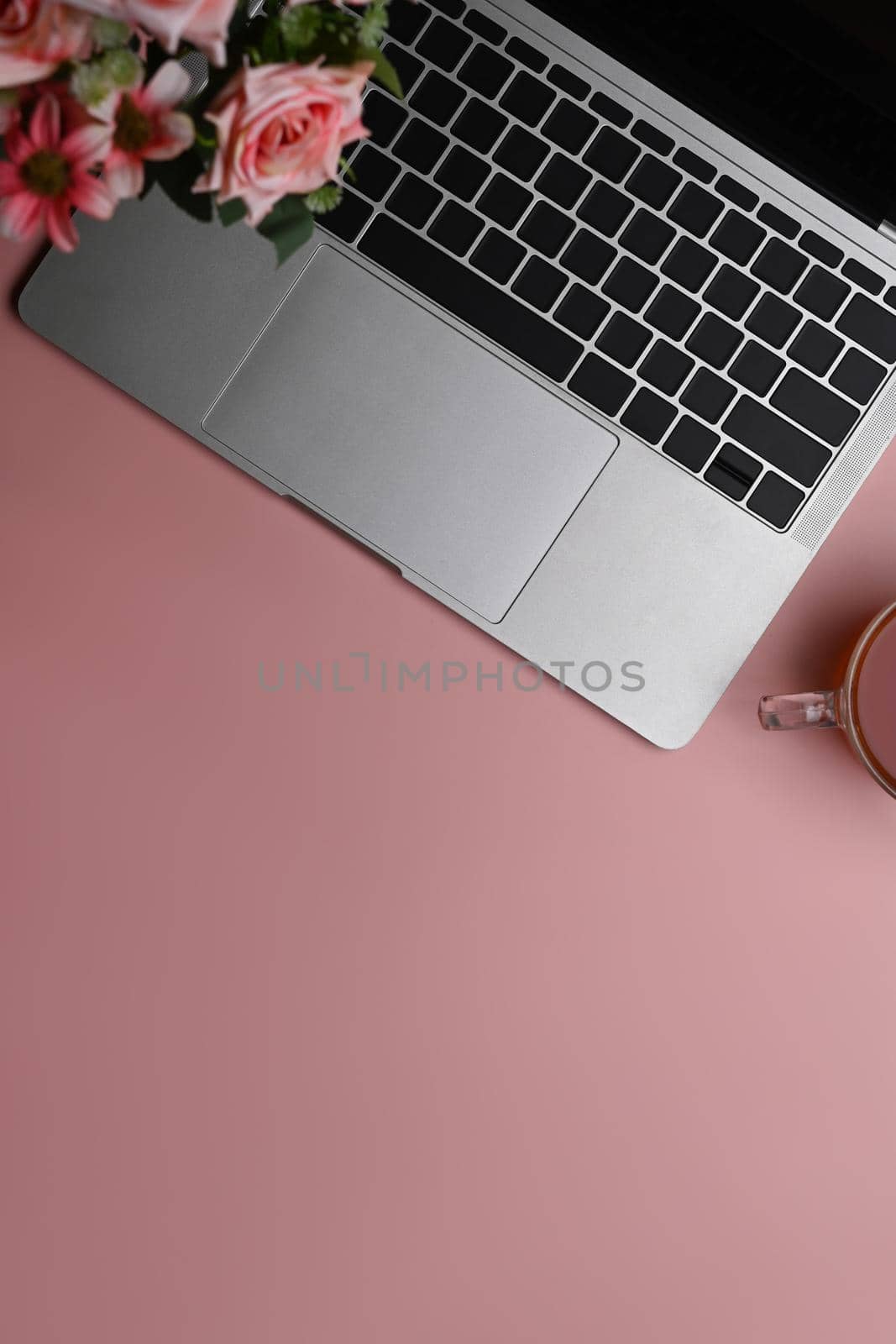 Feminine workspace with laptop, rose flowers and coffee cup on pink background. Flat lay ,Copy space.