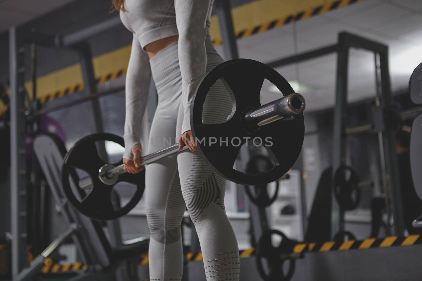 Low angle cropped shot of unrecognizable sportswoman lifting heavy barbell at the gym