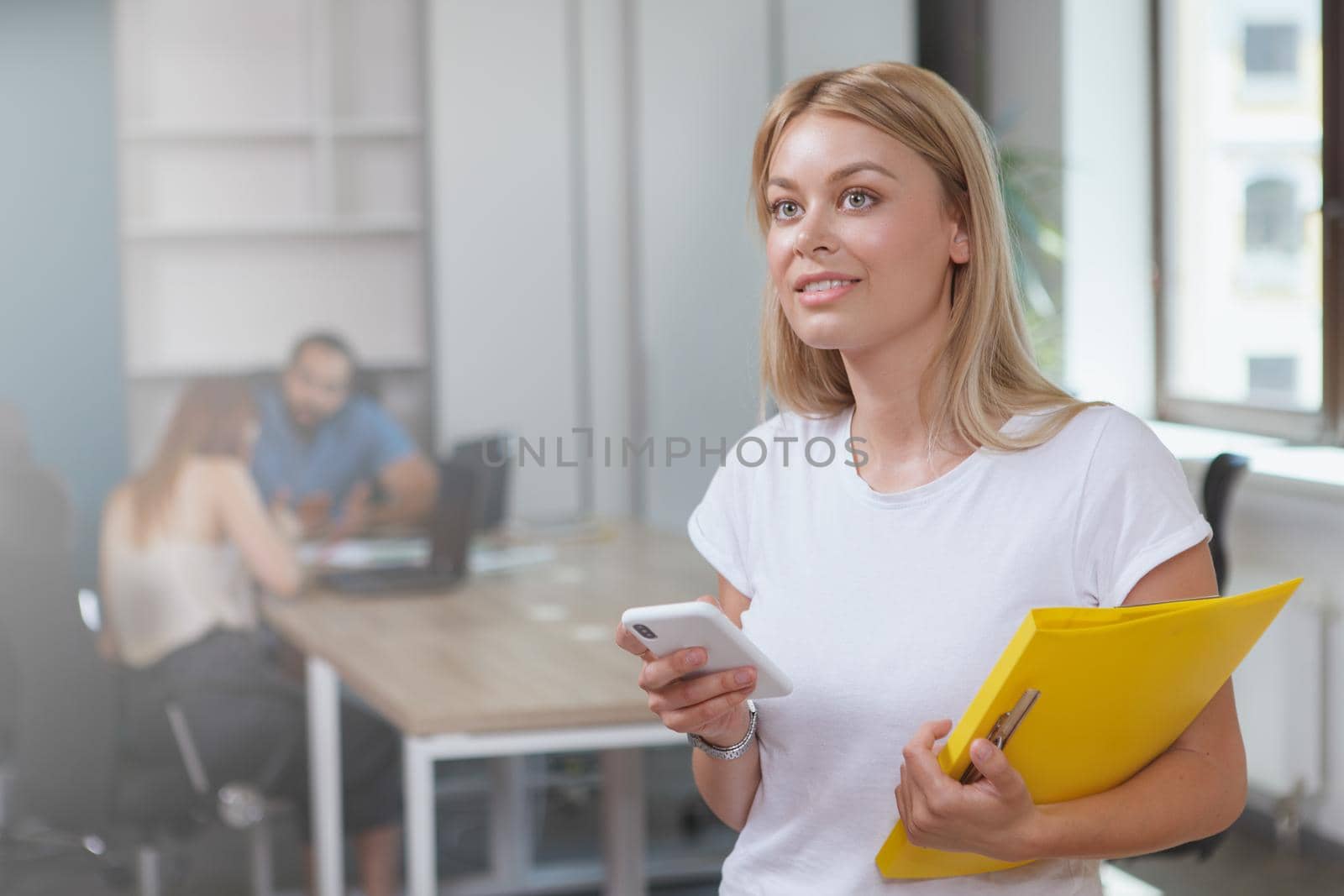 Cheerful young businesswoman smiling joyfully, holding her smart phone
