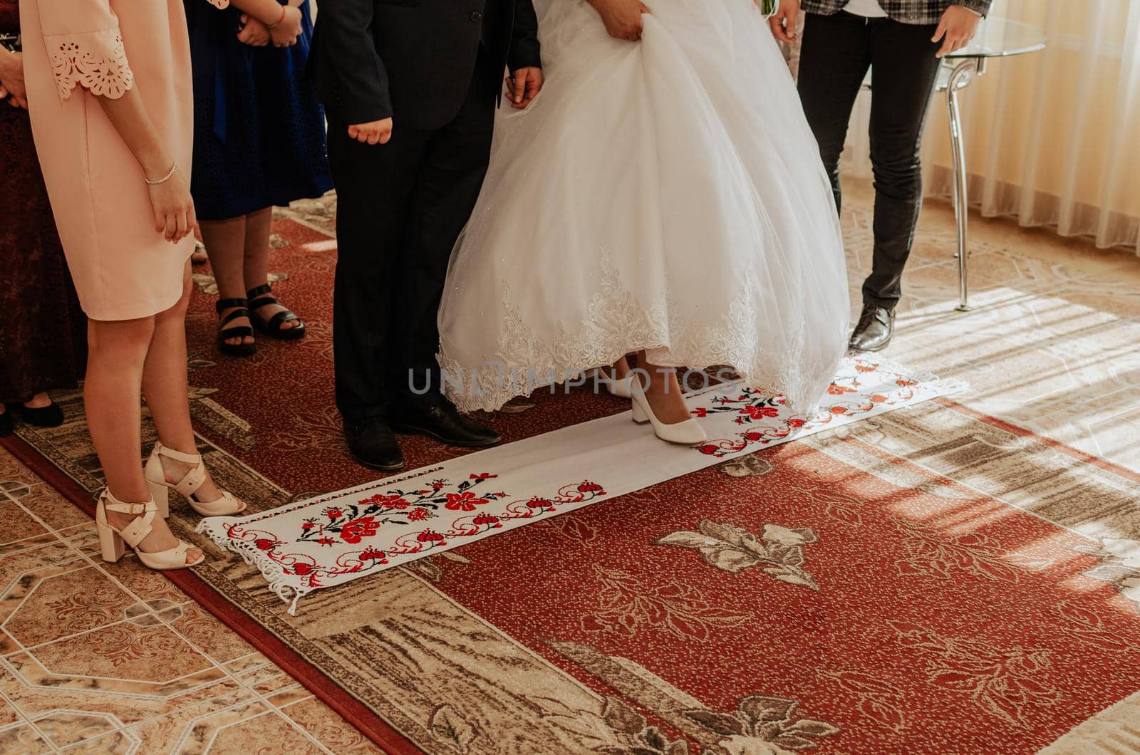 The bride and groom take a step on white national towels. Ukrainian national ornament embroidered.