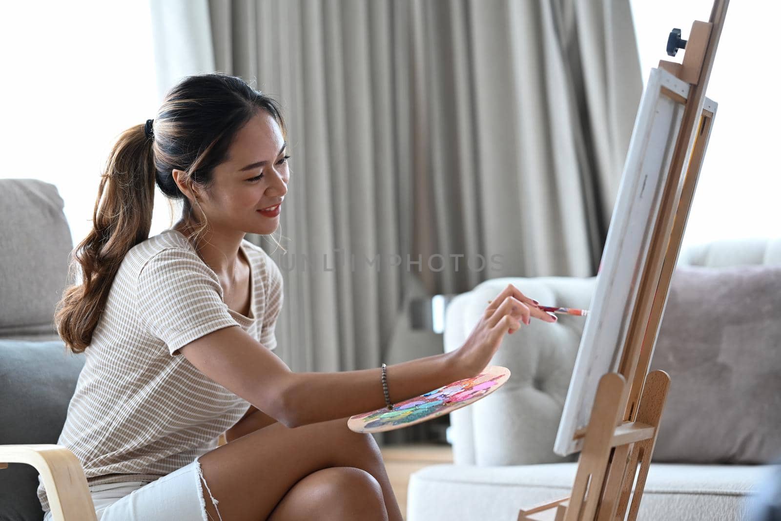 Attractive asian woman in casual clothes sitting in living room and enjoy creating her artwork.