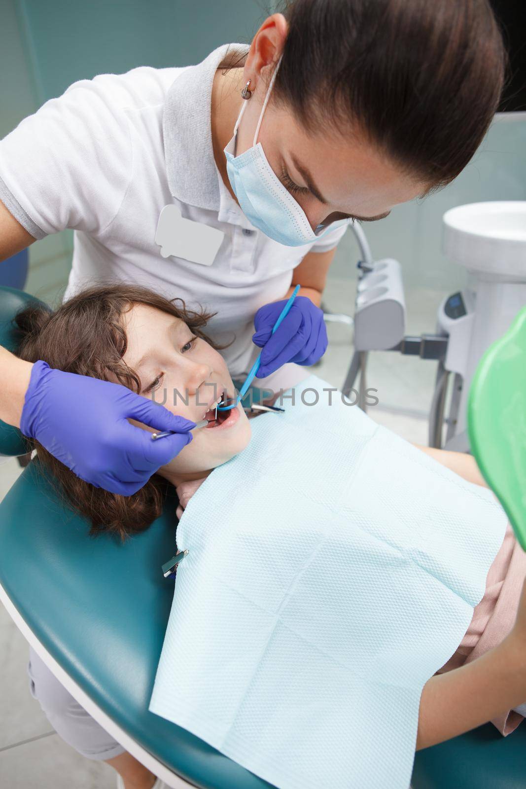 Vertical shot of a professional dentist examining teeth of young boy
