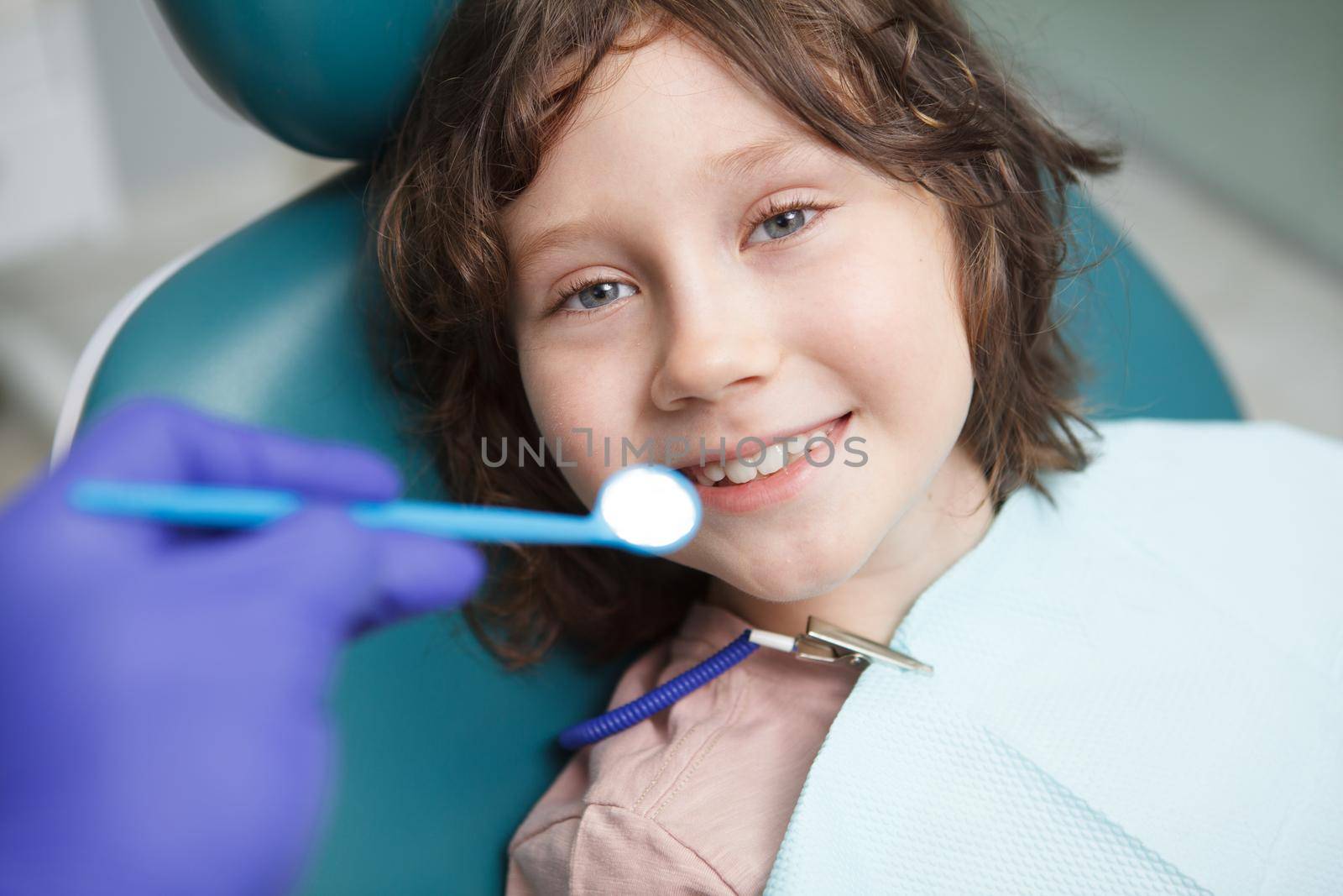 Close up of a young boy smiling, getting his teeth checked by dentist