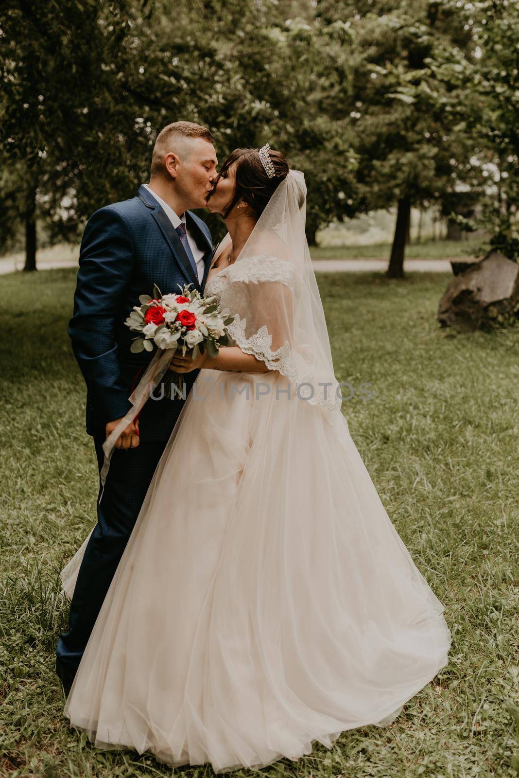 blonde European Caucasian young man groom in blue suit and black-haired woman bride in white wedding dress with long veil and tiara on head. first meeting newlyweds groom wait sees bride